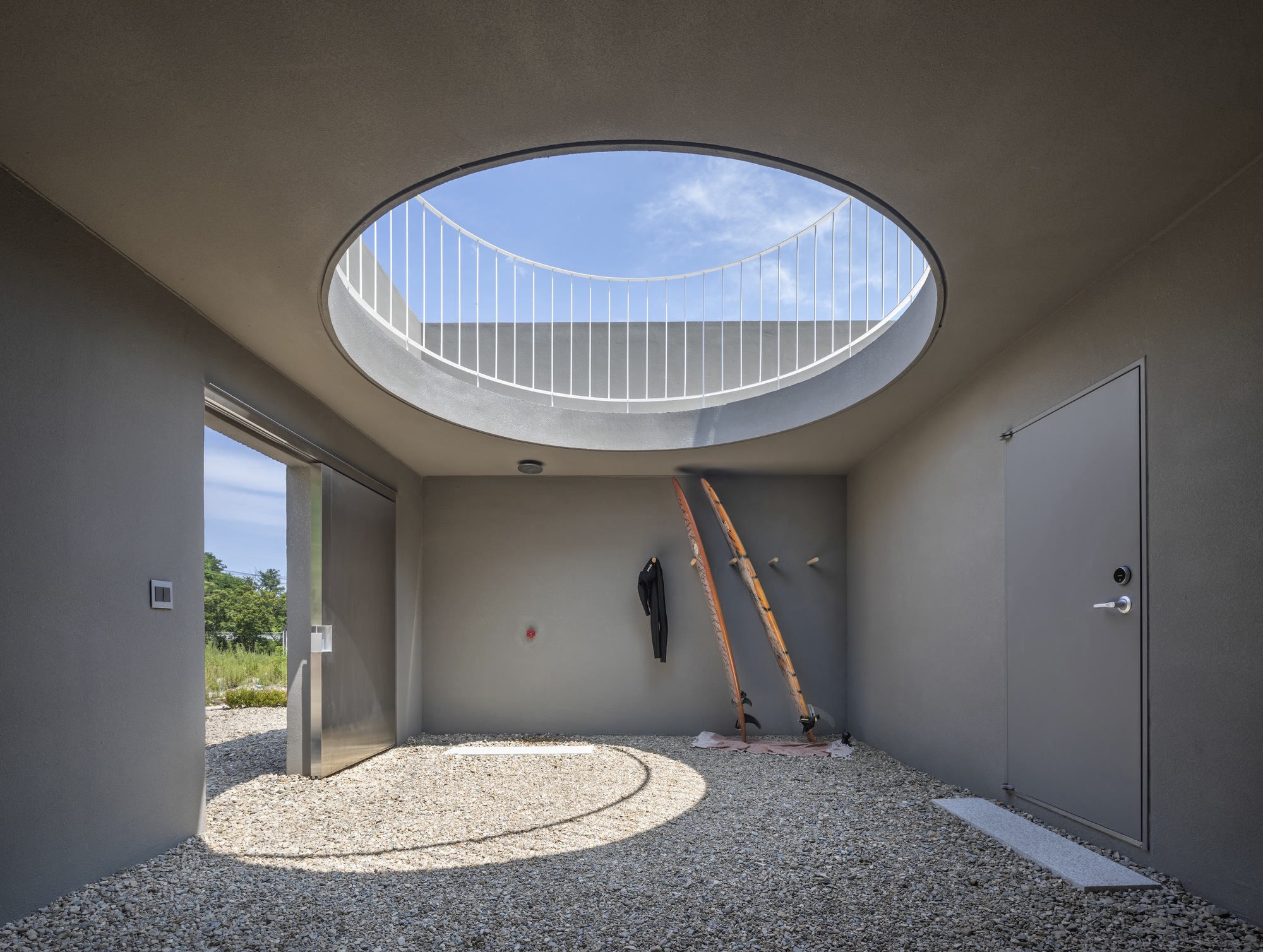 Interior courtyard with circular skylight framing white metal railing and wooden ladders against wall