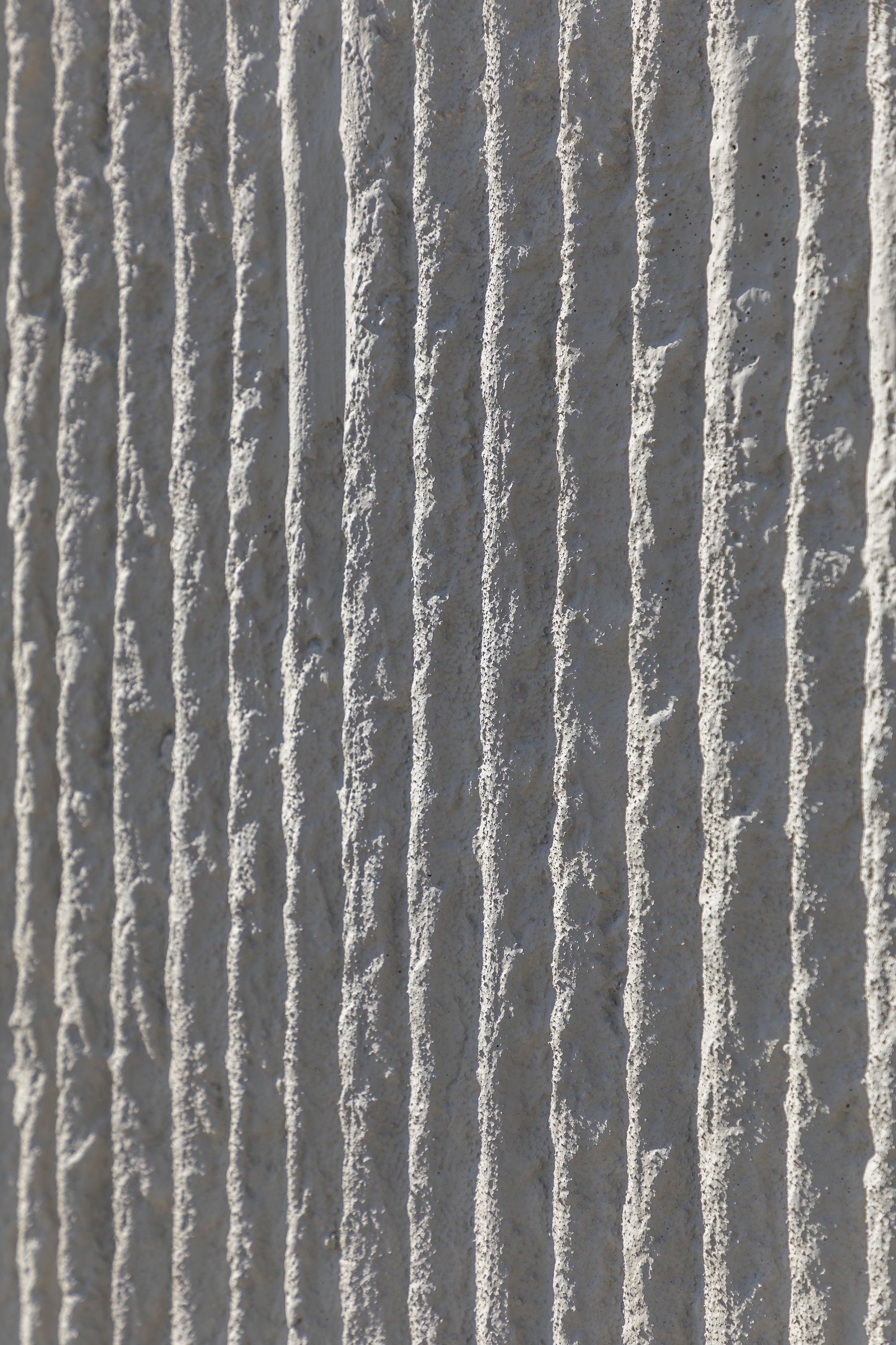 Close-up of vertical ribbed concrete surface showing textured formwork pattern in natural light