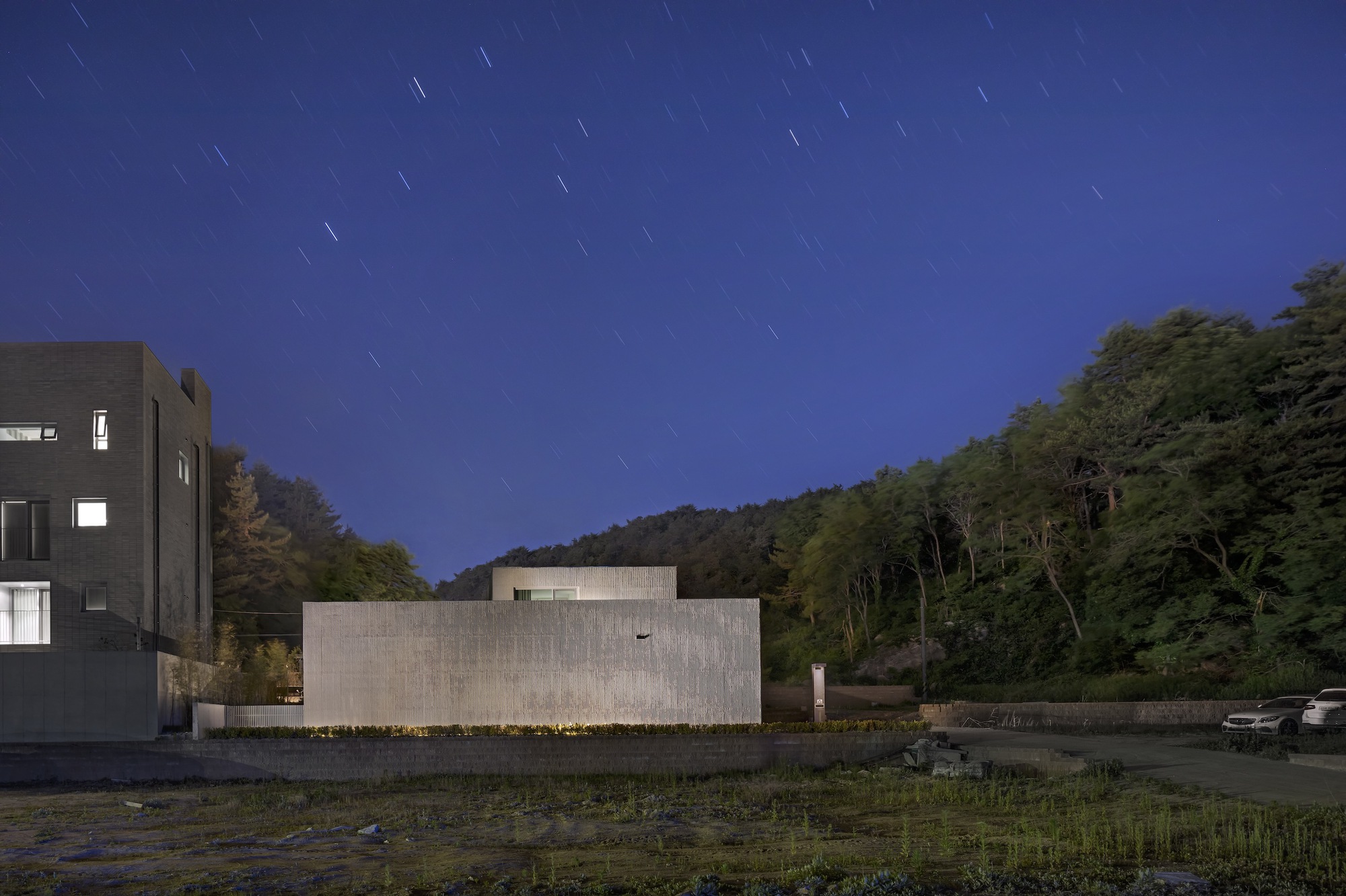Long exposure of the ribbed concrete facade under a deep blue sky with star trails