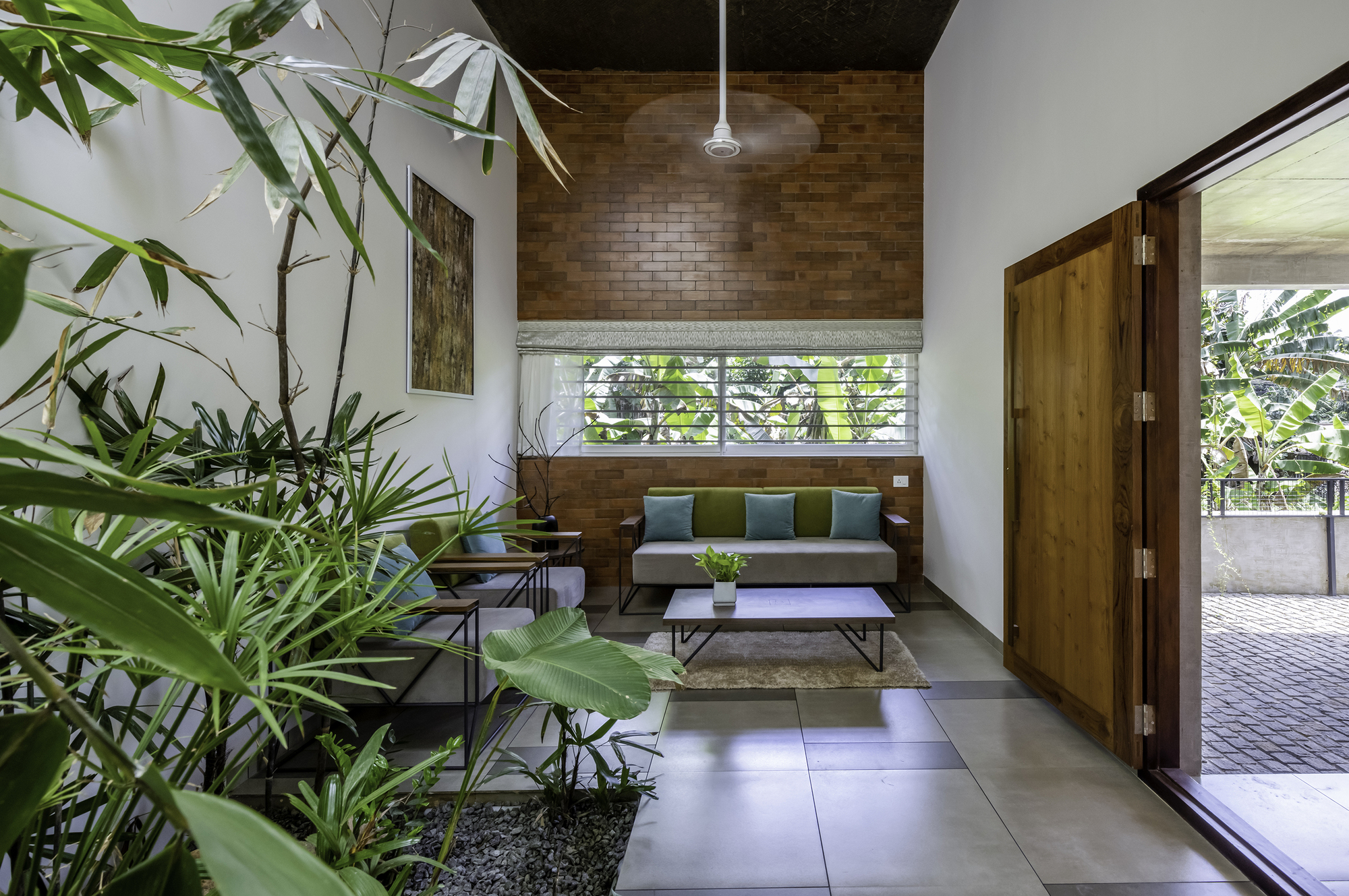 Living room with timber brick accent wall and interior bamboo planting beside large floor tiles