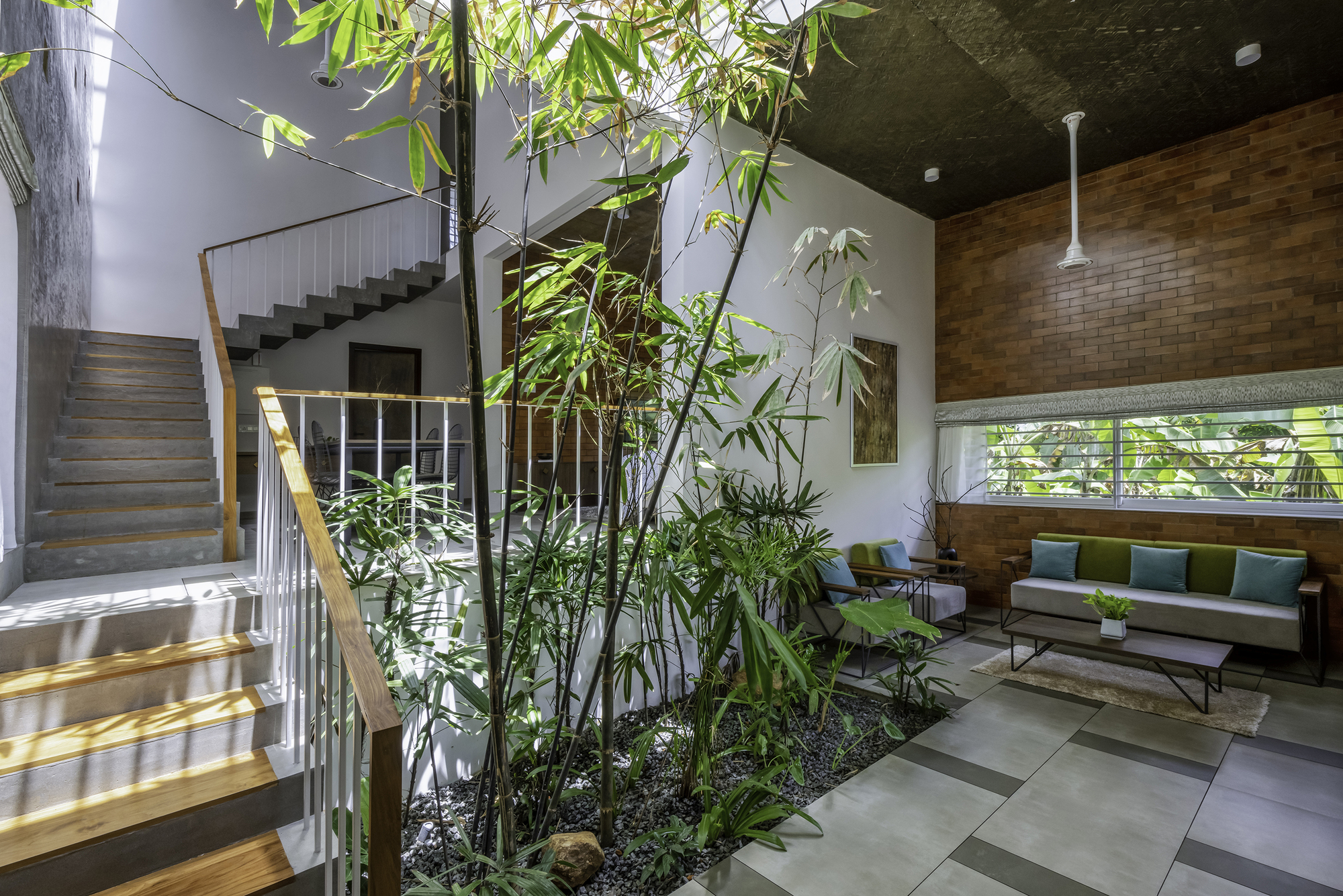Interior living space with bamboo planting bed, concrete stair and dappled sunlight through overhead screening