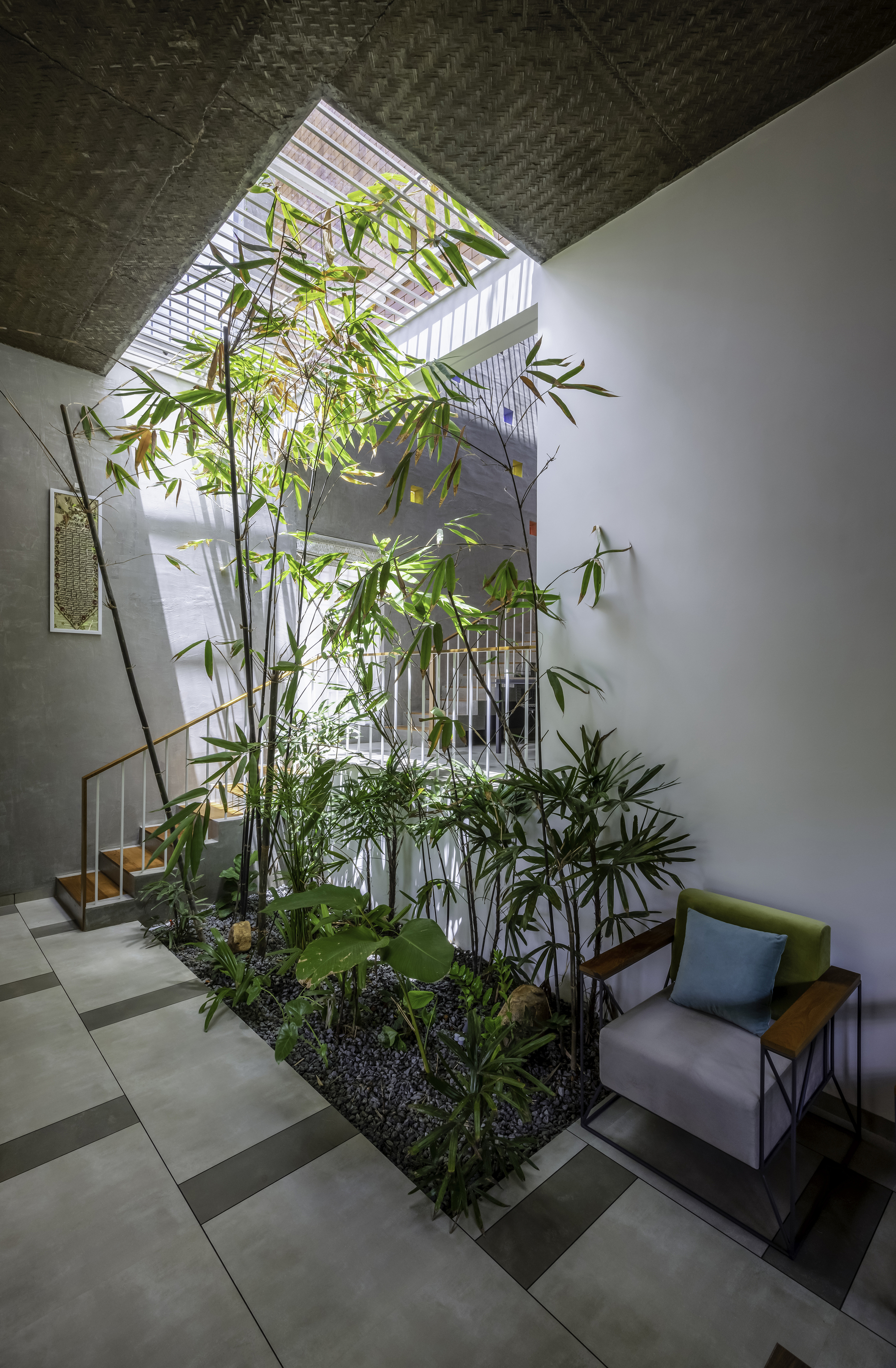 Double-height interior courtyard with bamboo grove and skylight above the stair void