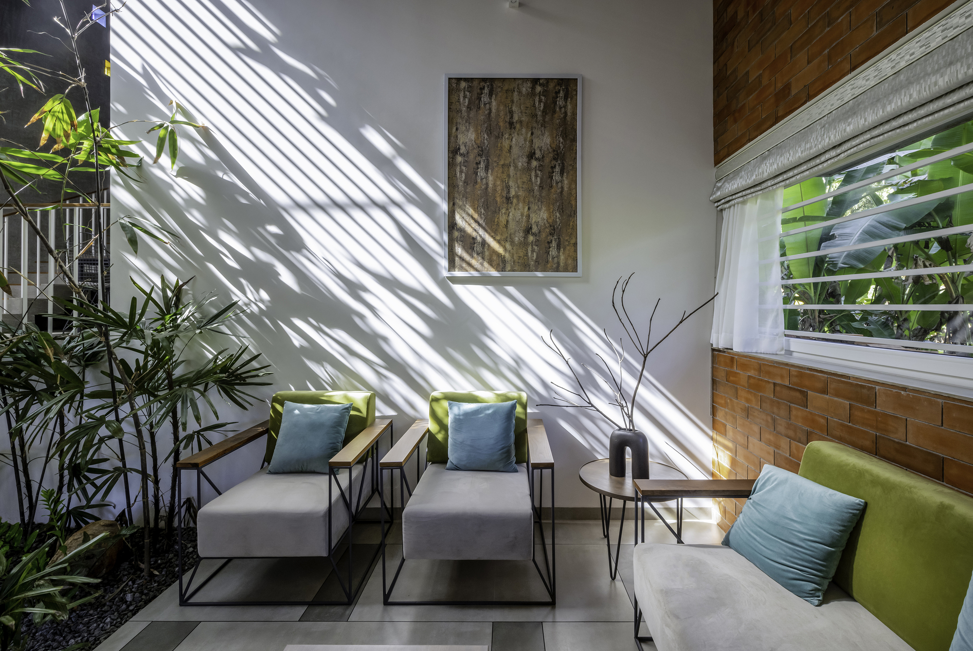 Seating area with striped shadow patterns from louvered skylight falling across white wall