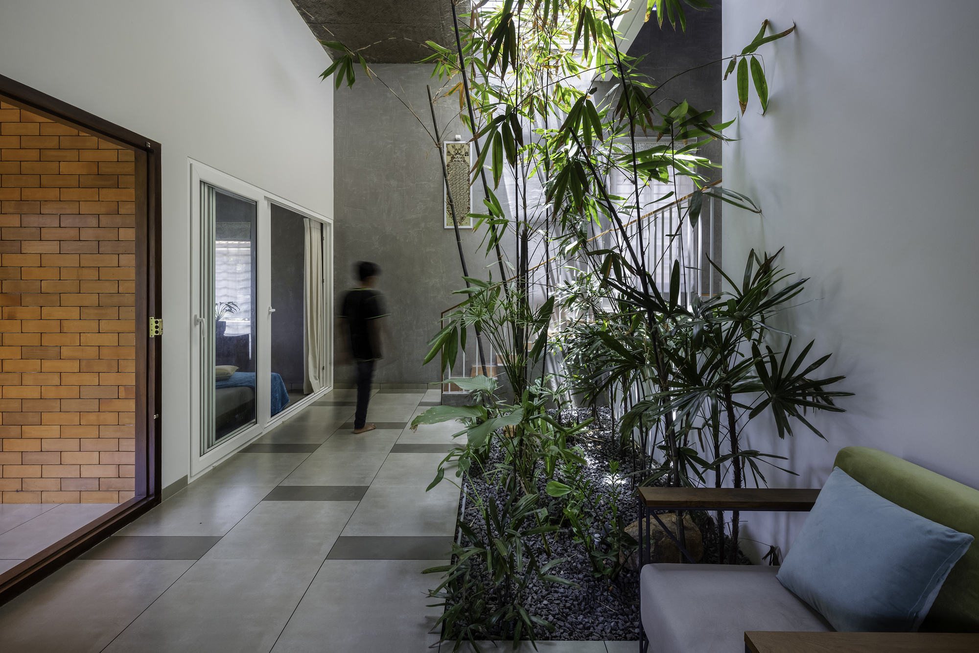 Ground floor passage with planted interior courtyard and figure in motion through doorway