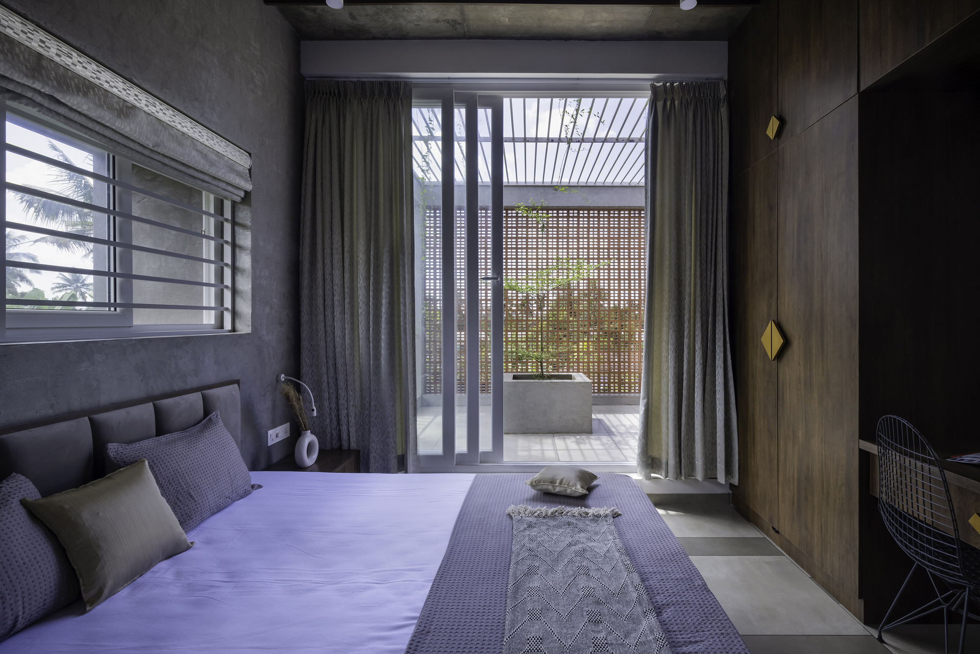Bedroom looking toward a curtained opening with slatted screen beyond and perforated metal panel beyond