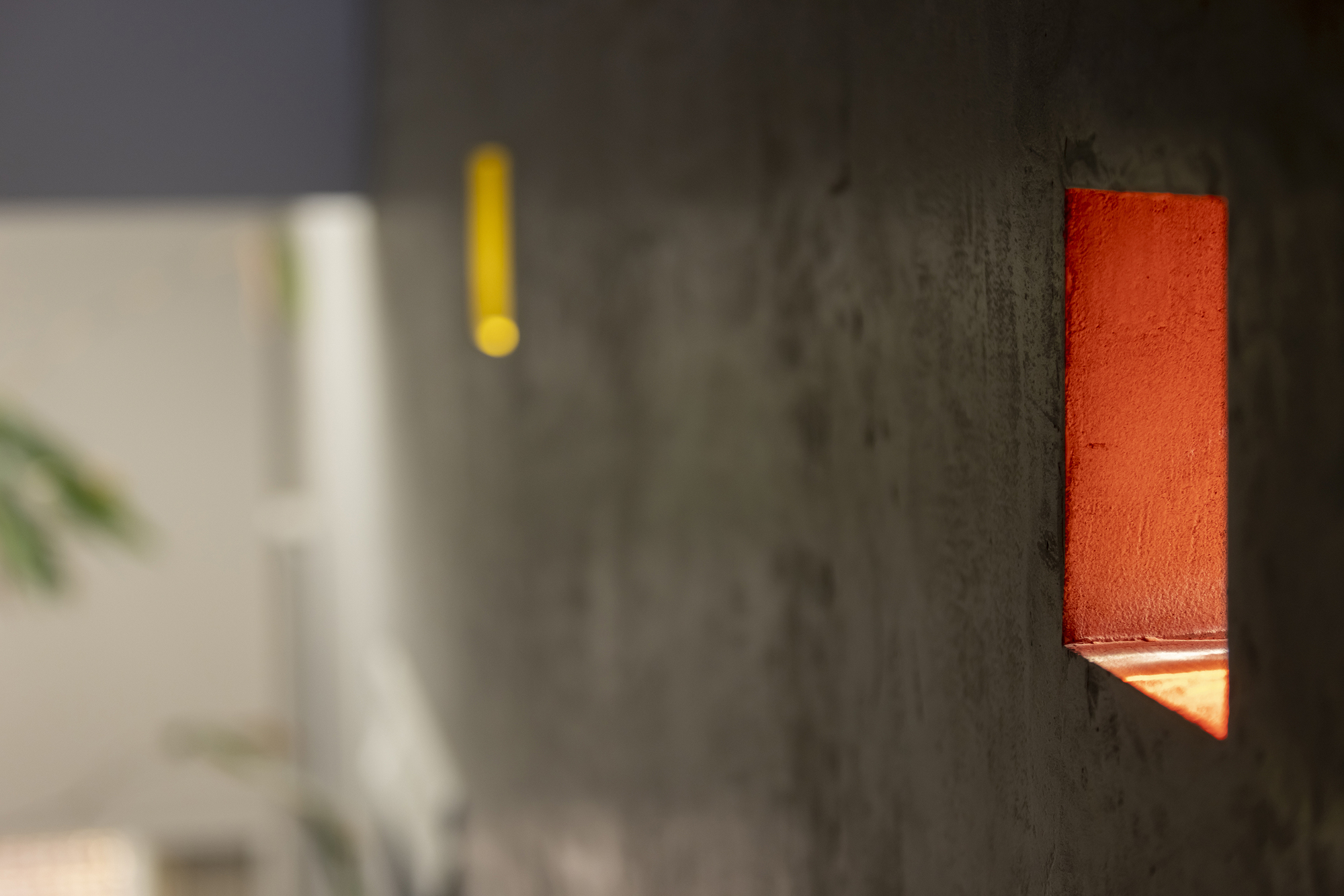 Close-up of an orange sconce set into a textured concrete wall