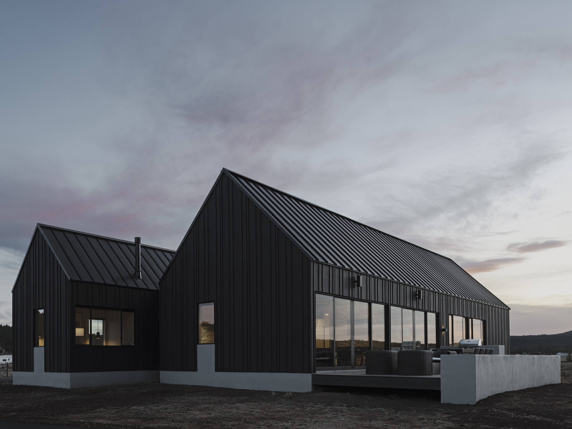 Glazed south facade with continuous ribbon windows and white concrete planters at dusk