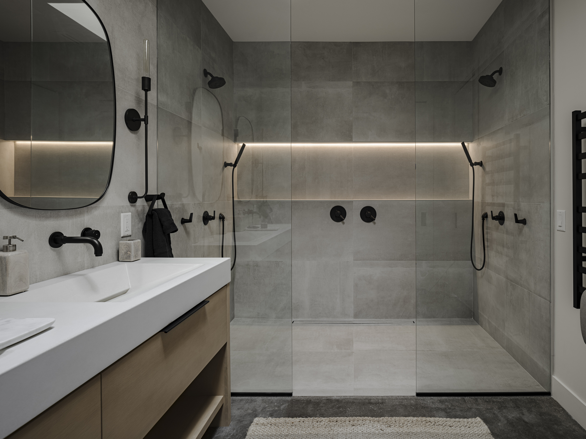 Double shower enclosure with horizontal strip lighting and grey tile walls