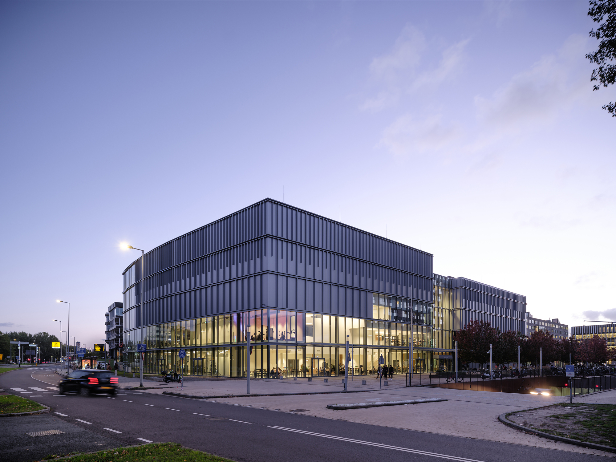 Corner view of the illuminated glass base and vertical metal facade at dusk