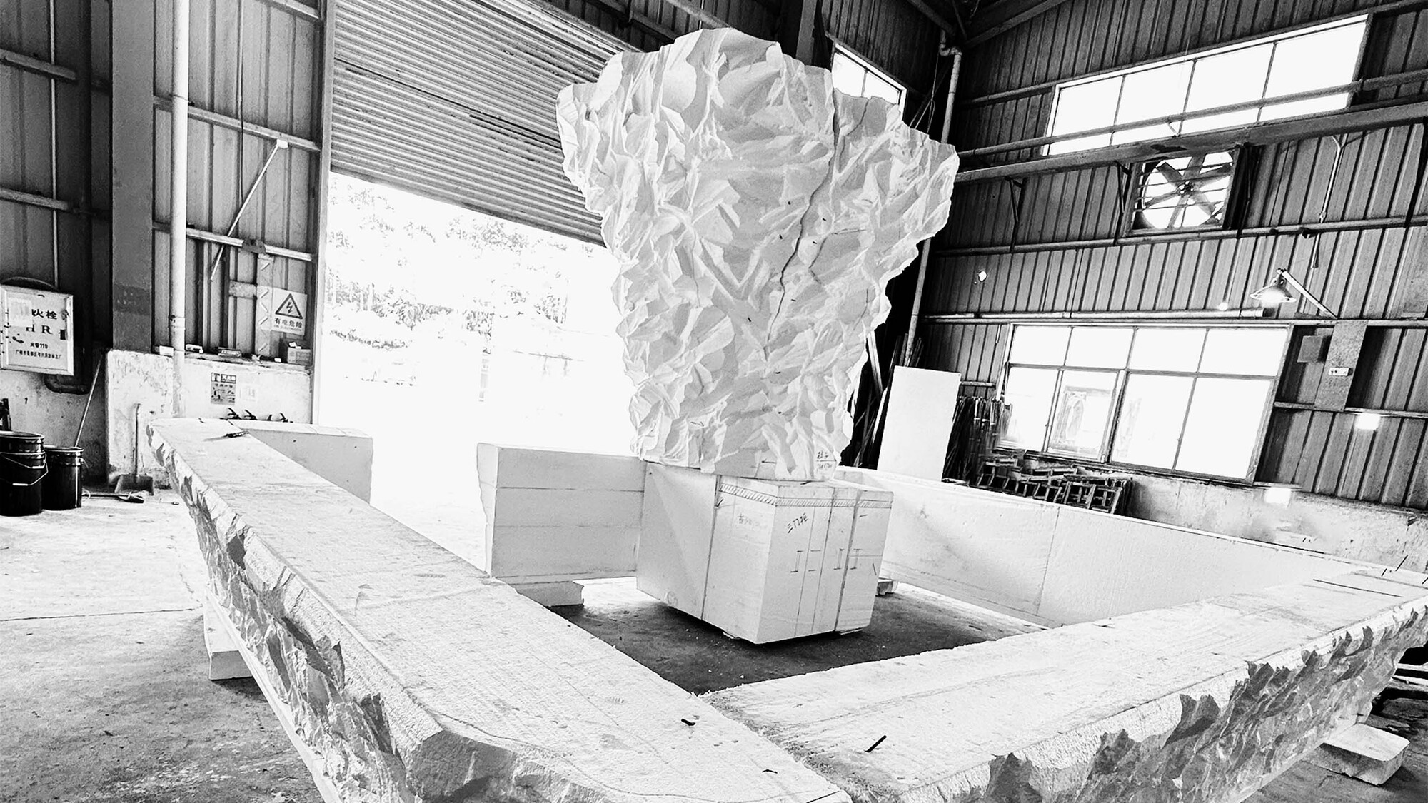 Carved foam mockup of a faceted column displayed on a workbench in a warehouse studio