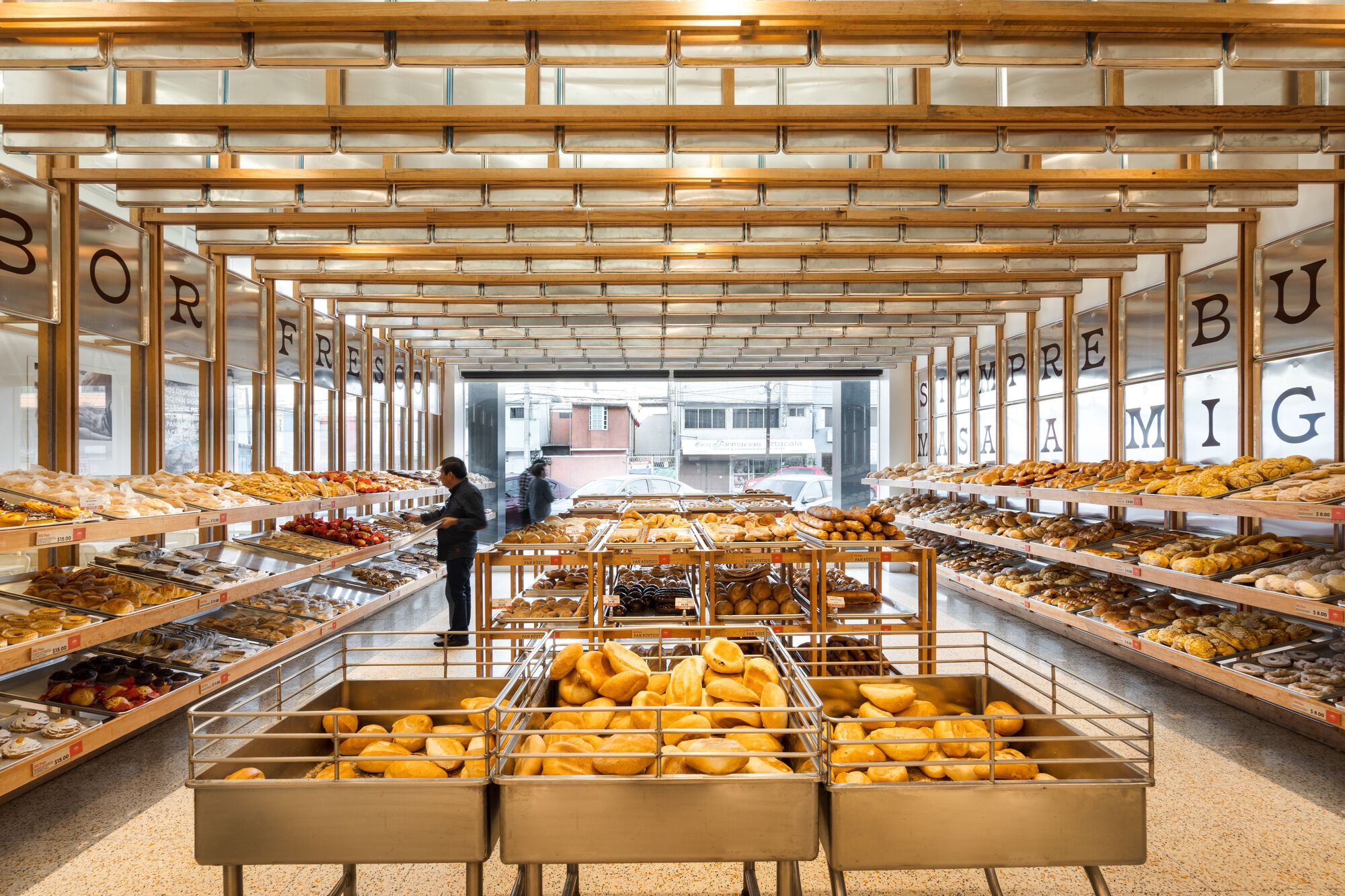 Interior view of bakery with timber grid ceiling and parallel display tables loaded with bread