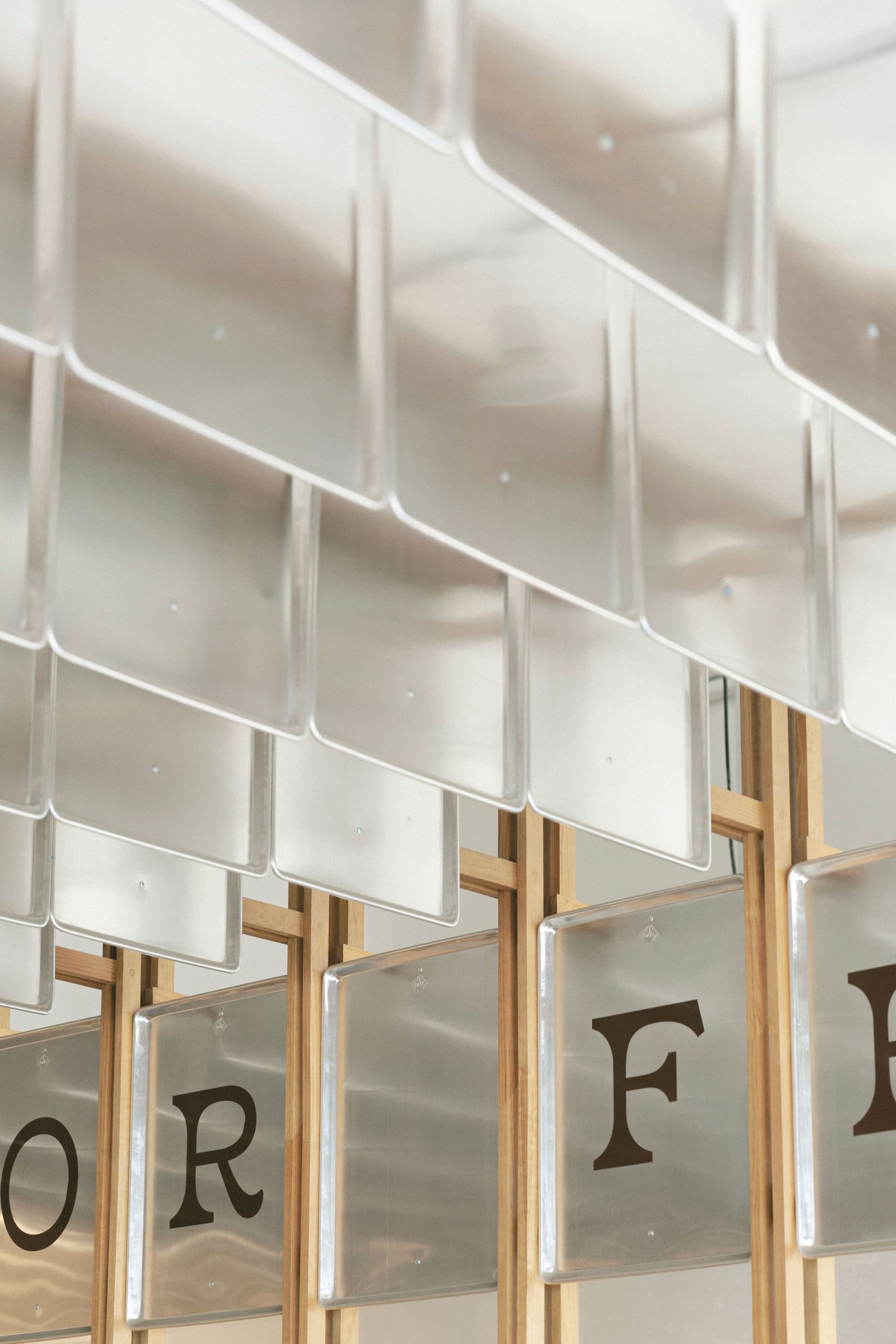 Detail of white ceramic tile shingles overlapping above timber framing and printed glass panels