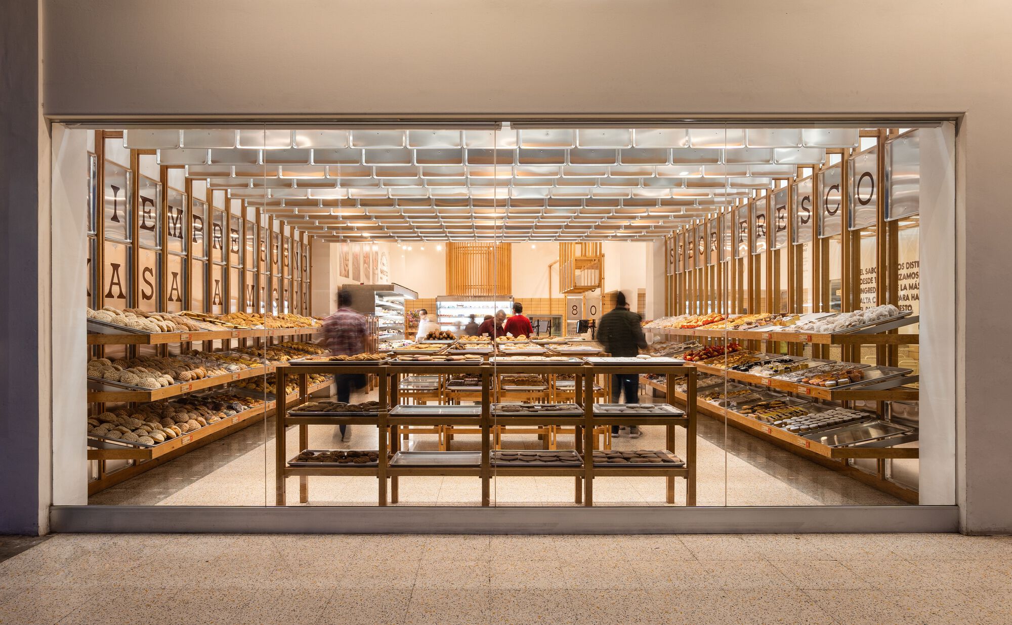 Street view through the glass storefront into the timber-framed bakery with customers browsing