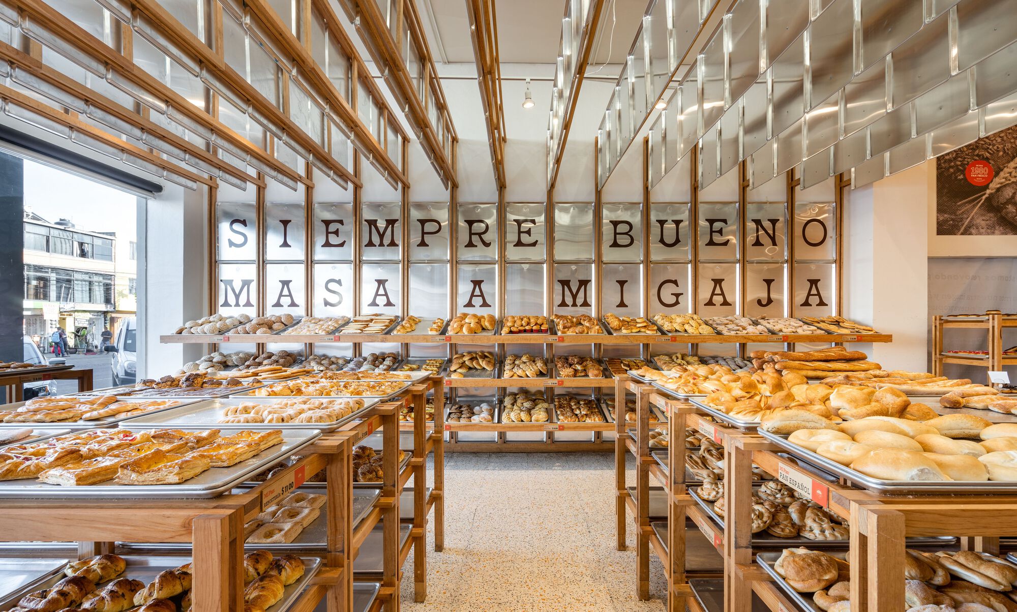 Interior view of the bakery displaying timber display tables beneath letterforms suspended from the ceiling