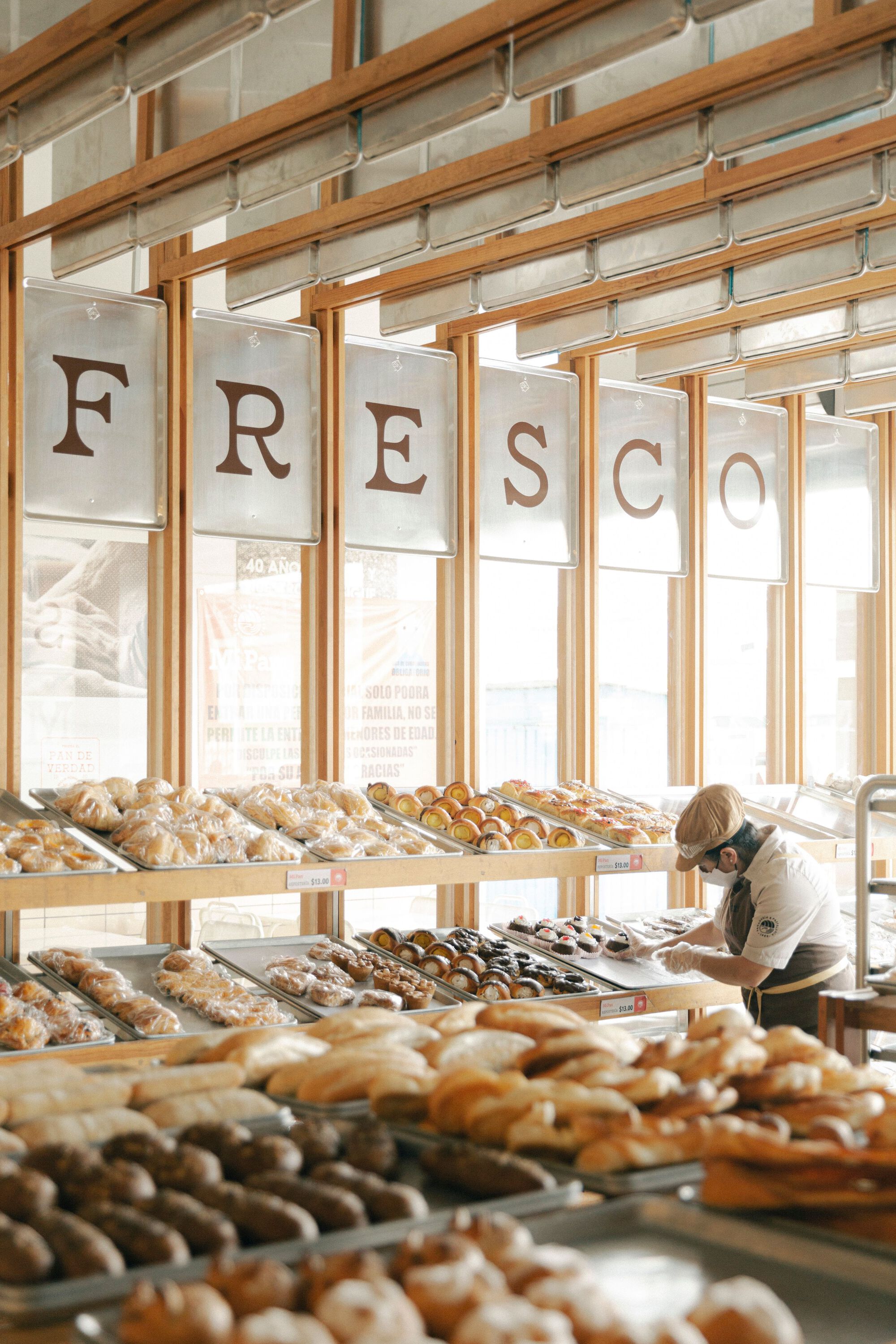 Angled view of the display tables loaded with pastries and a customer in afternoon light