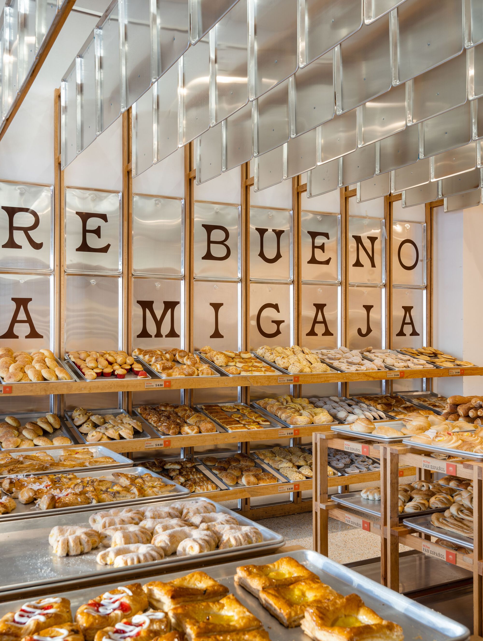 Corner perspective showing tiered shelves of pastries beneath the suspended translucent panel wall