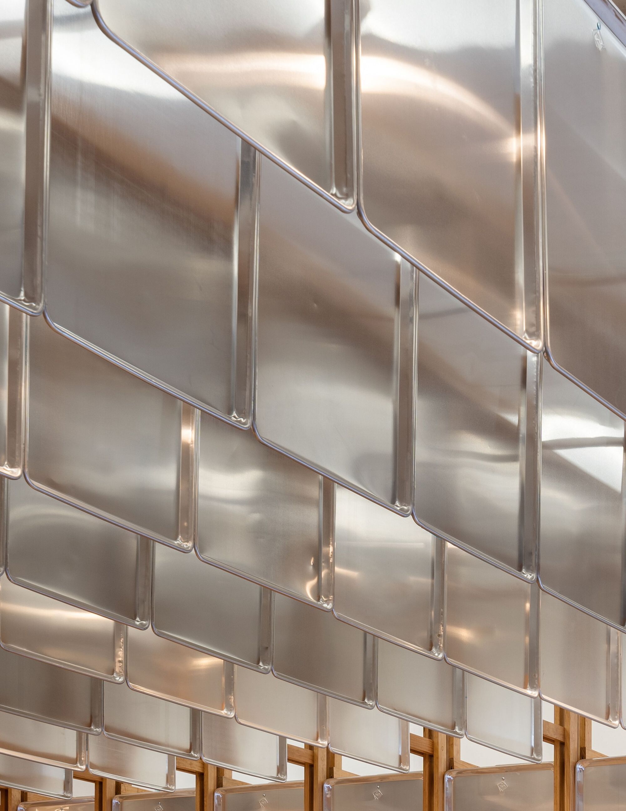 Close-up detail of the overlapping translucent glass panels with metal edge channels in herringbone pattern