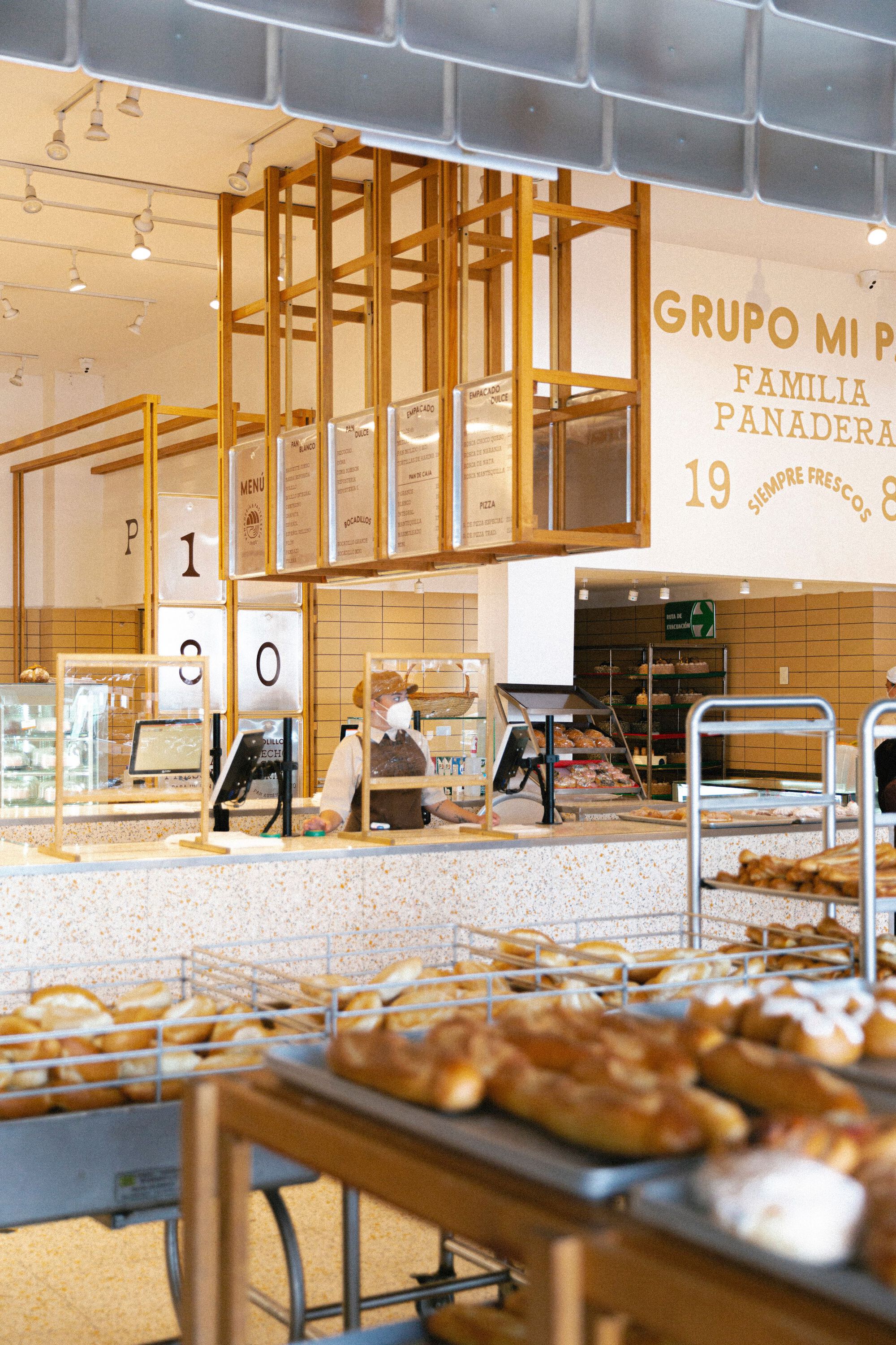 Bakery interior with timber frame canopy over the counter and trays of bread in the foreground