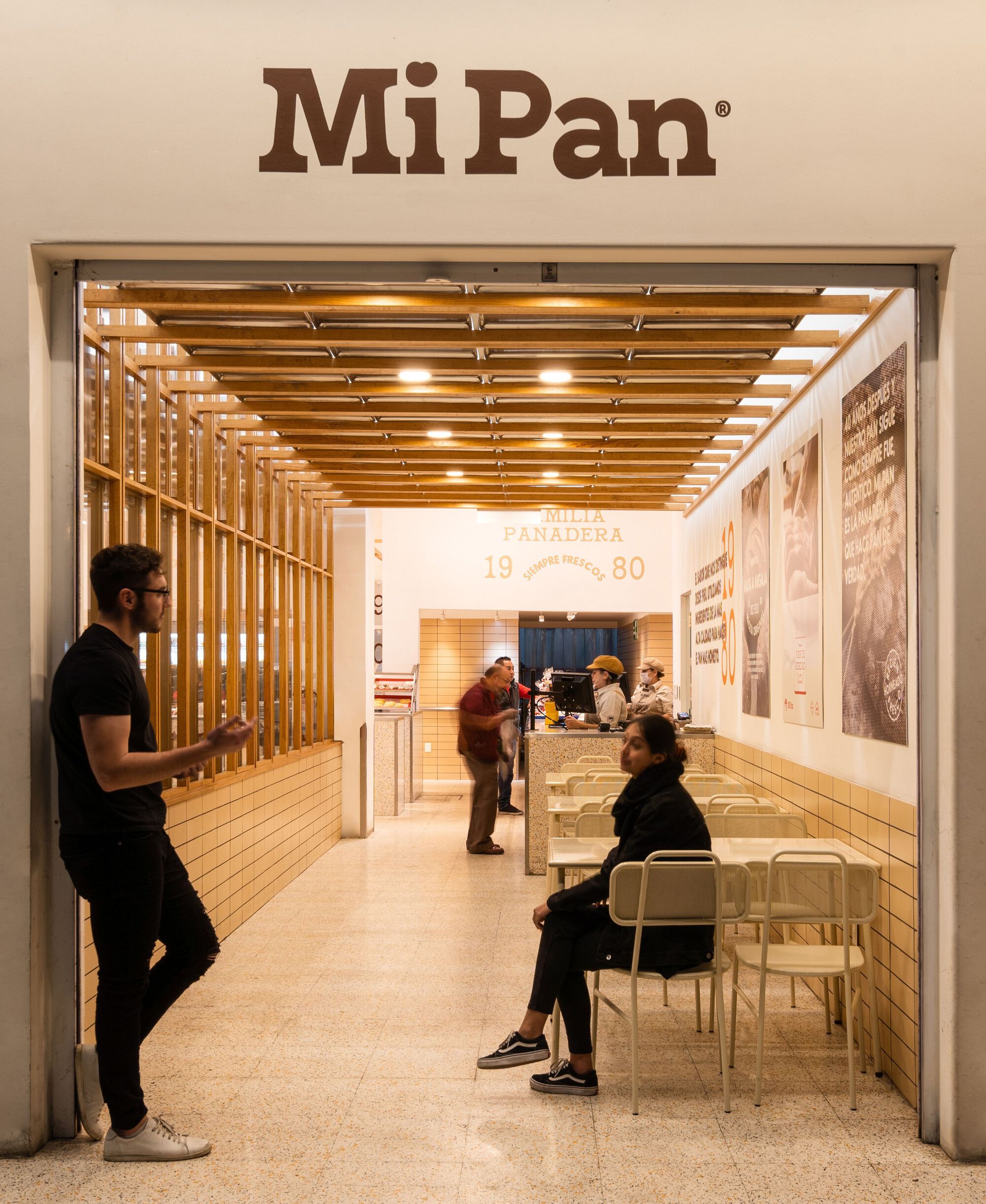 Entrance view with timber slat ceiling and customers seated at tables along the tiled wall