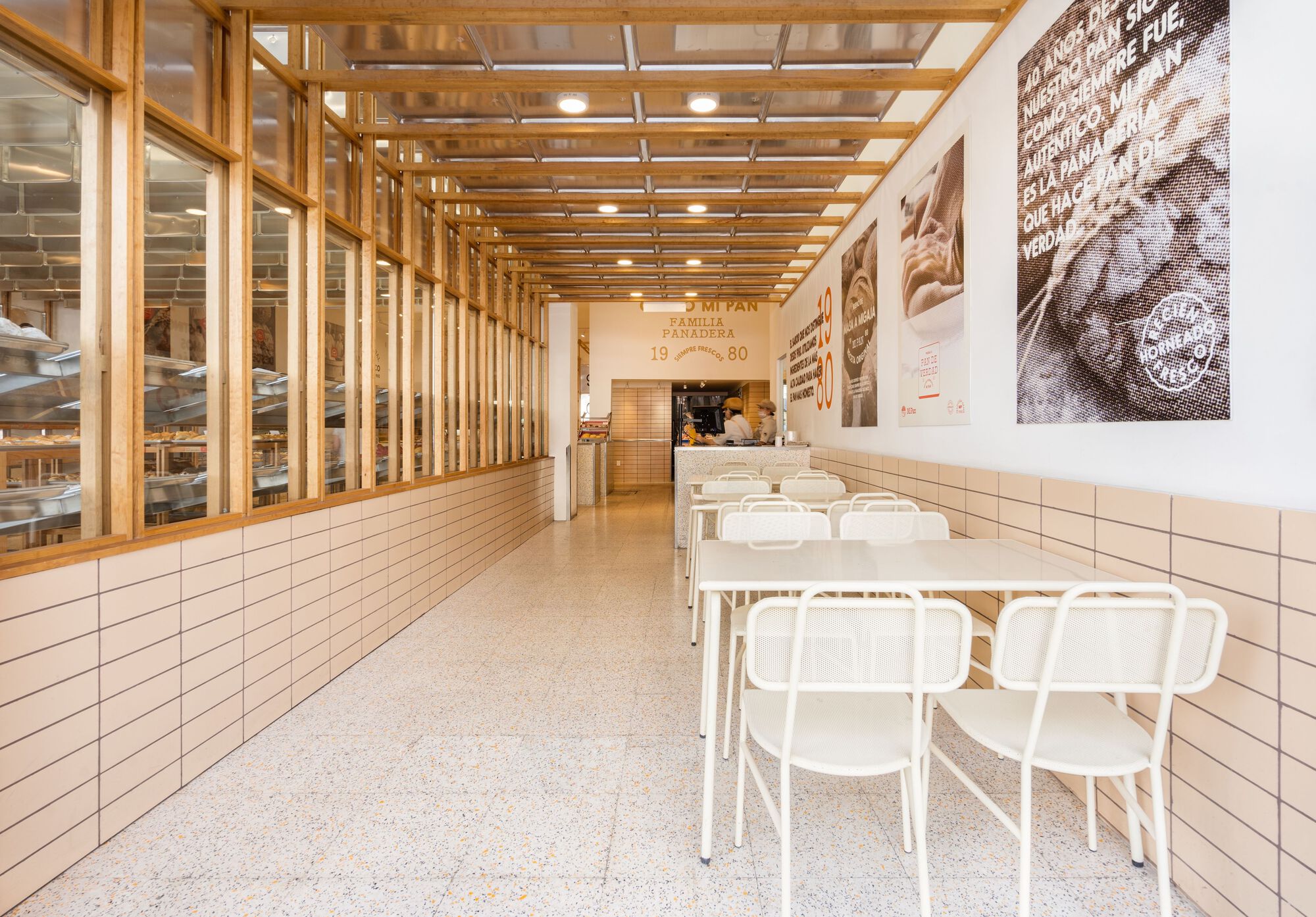 Dining area showing timber slat partition wall and terrazzo floor beneath the gridded wood ceiling