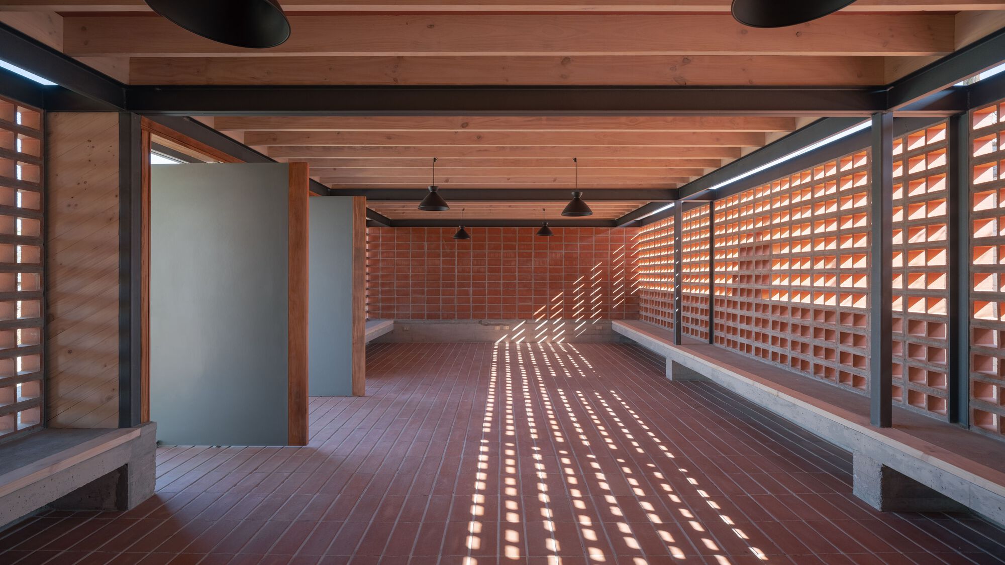 Interior room with light filtering through perforated block walls onto clay tile flooring