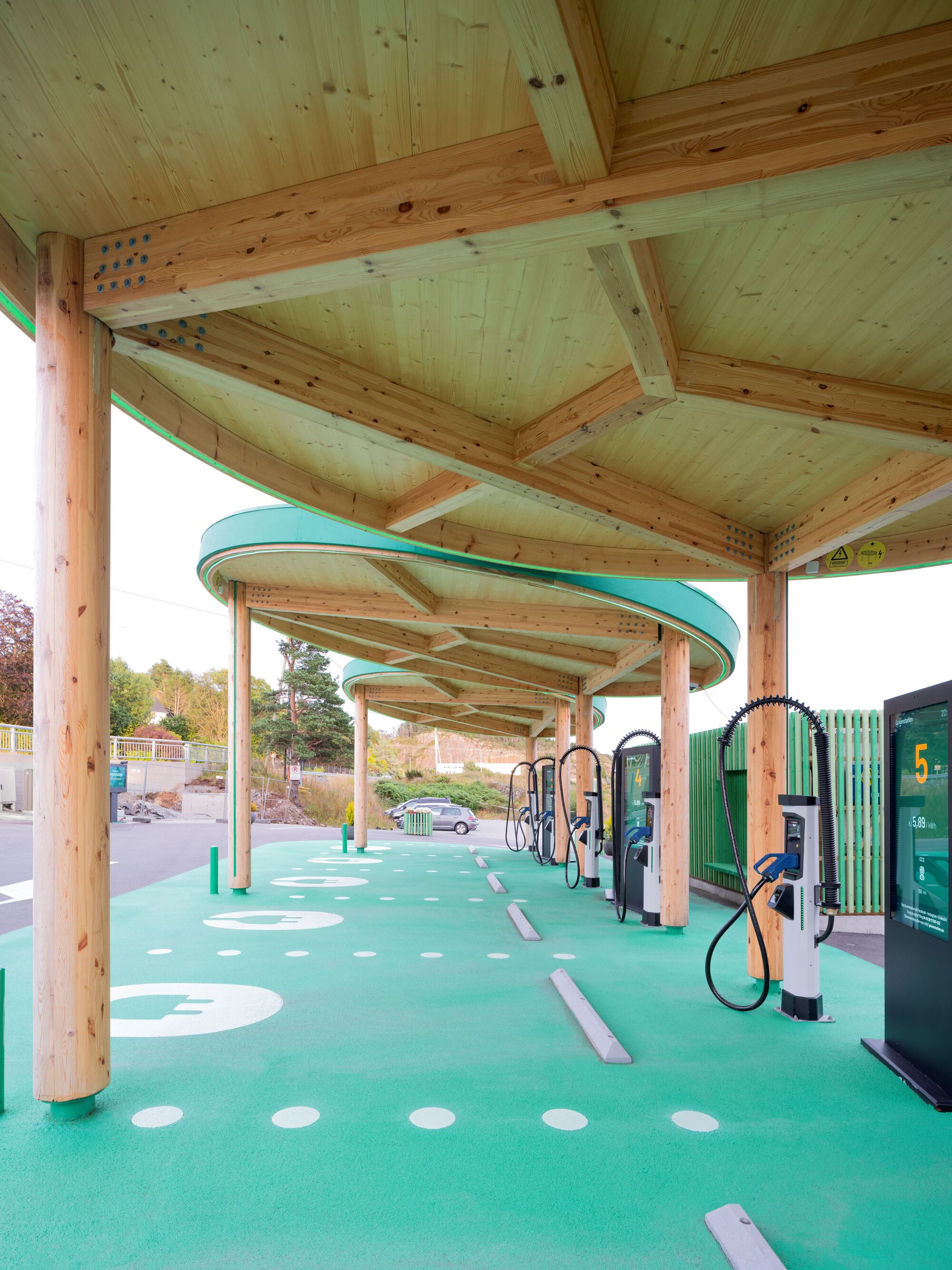 Underside view of the timber canopy structure showing exposed joinery and radiating beams over the charging stations