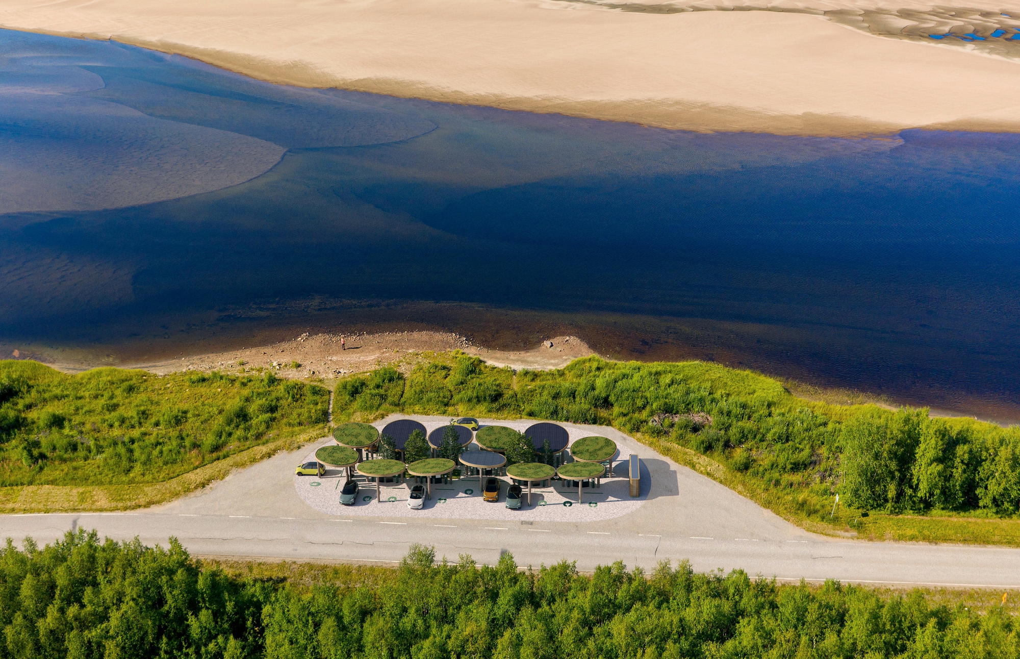 Aerial view of the charging station with circular canopies situated between a coastal road and the blue waterfront