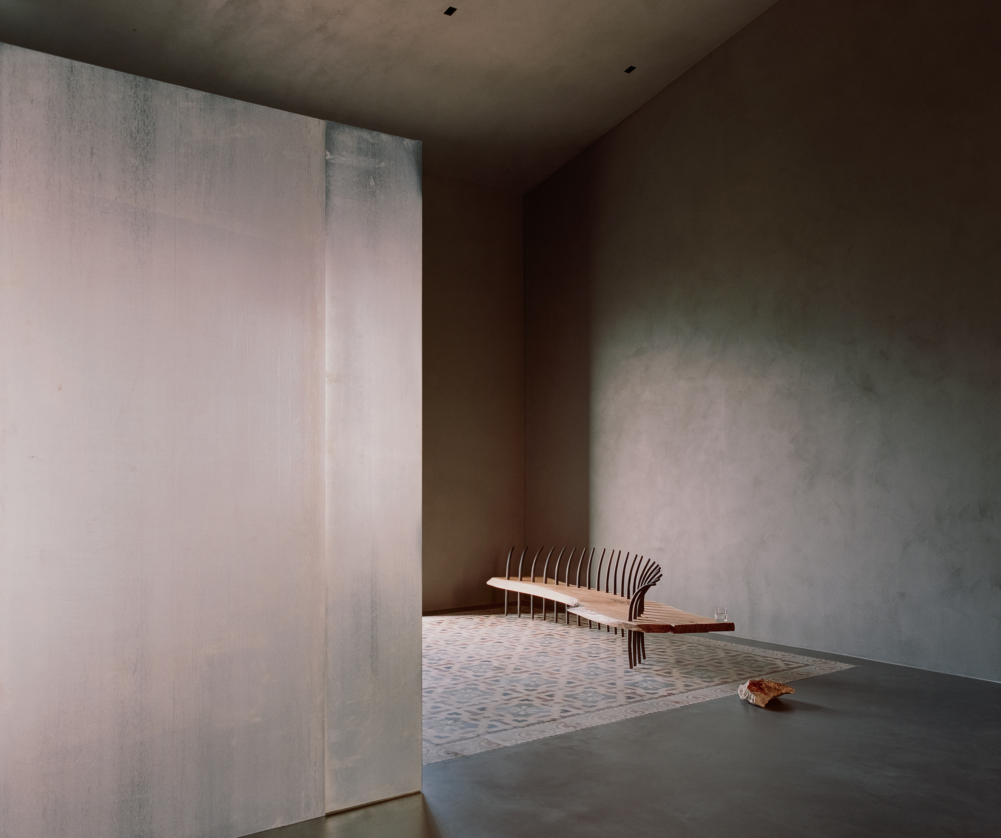 Interior room with slatted timber bench against rendered plaster walls with textured trowel marks