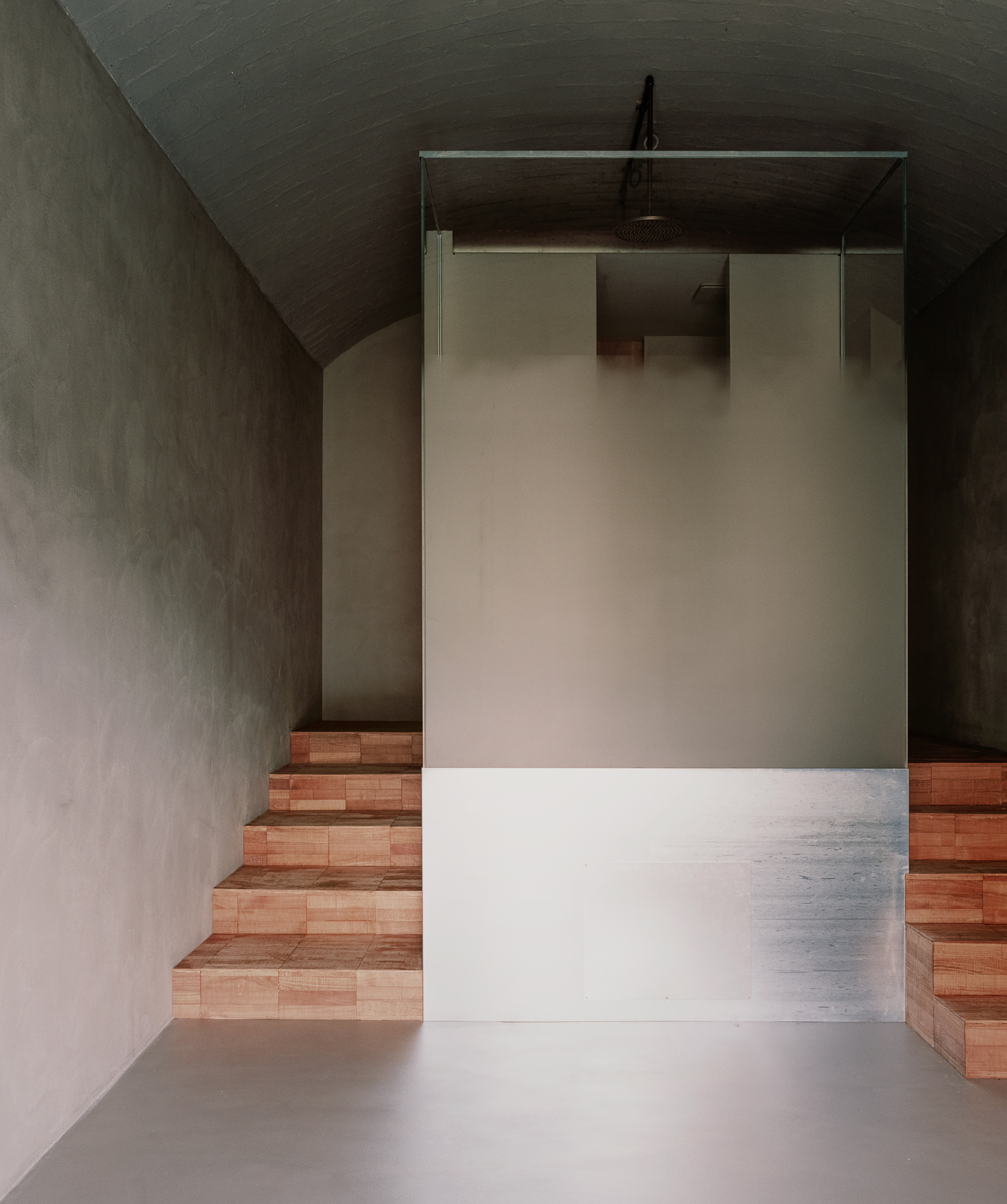 Timber-faced staircase framed by plastered walls and vaulted ceiling with soft overhead light