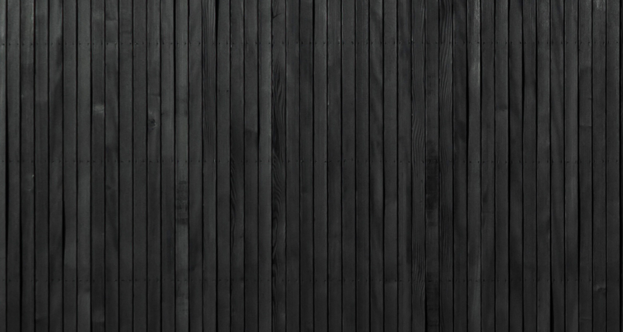 Close-up of vertical blackened timber cladding with fine parallel grooves