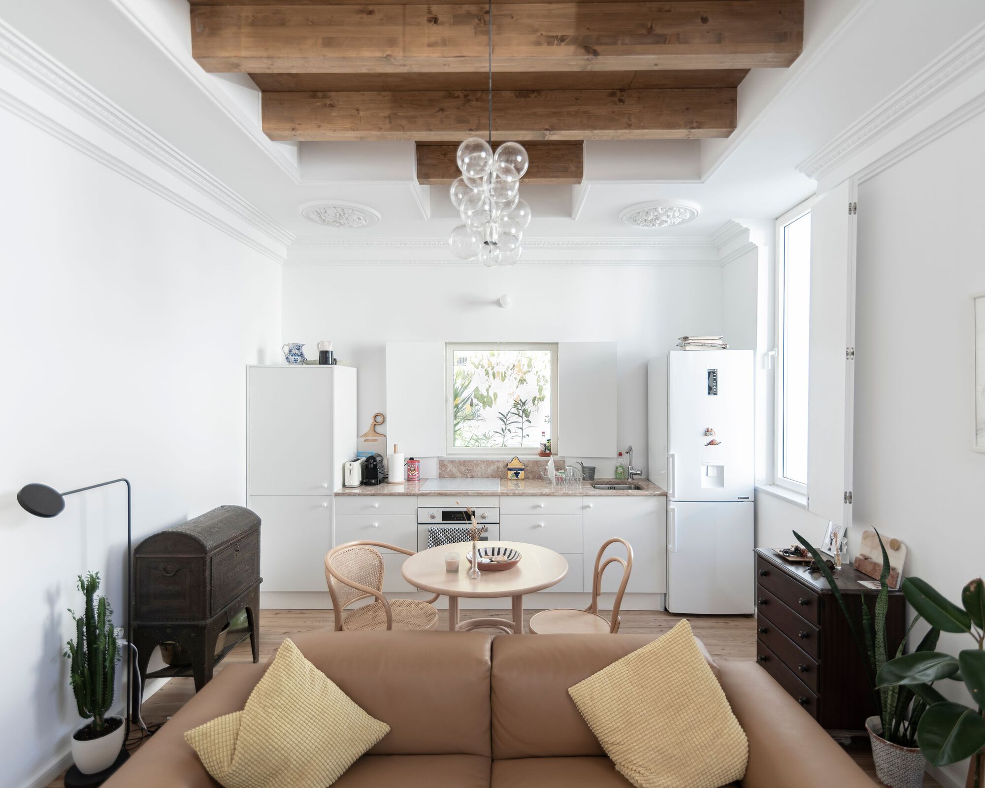 Open living and kitchen area with exposed timber ceiling beams and decorative plasterwork medallions