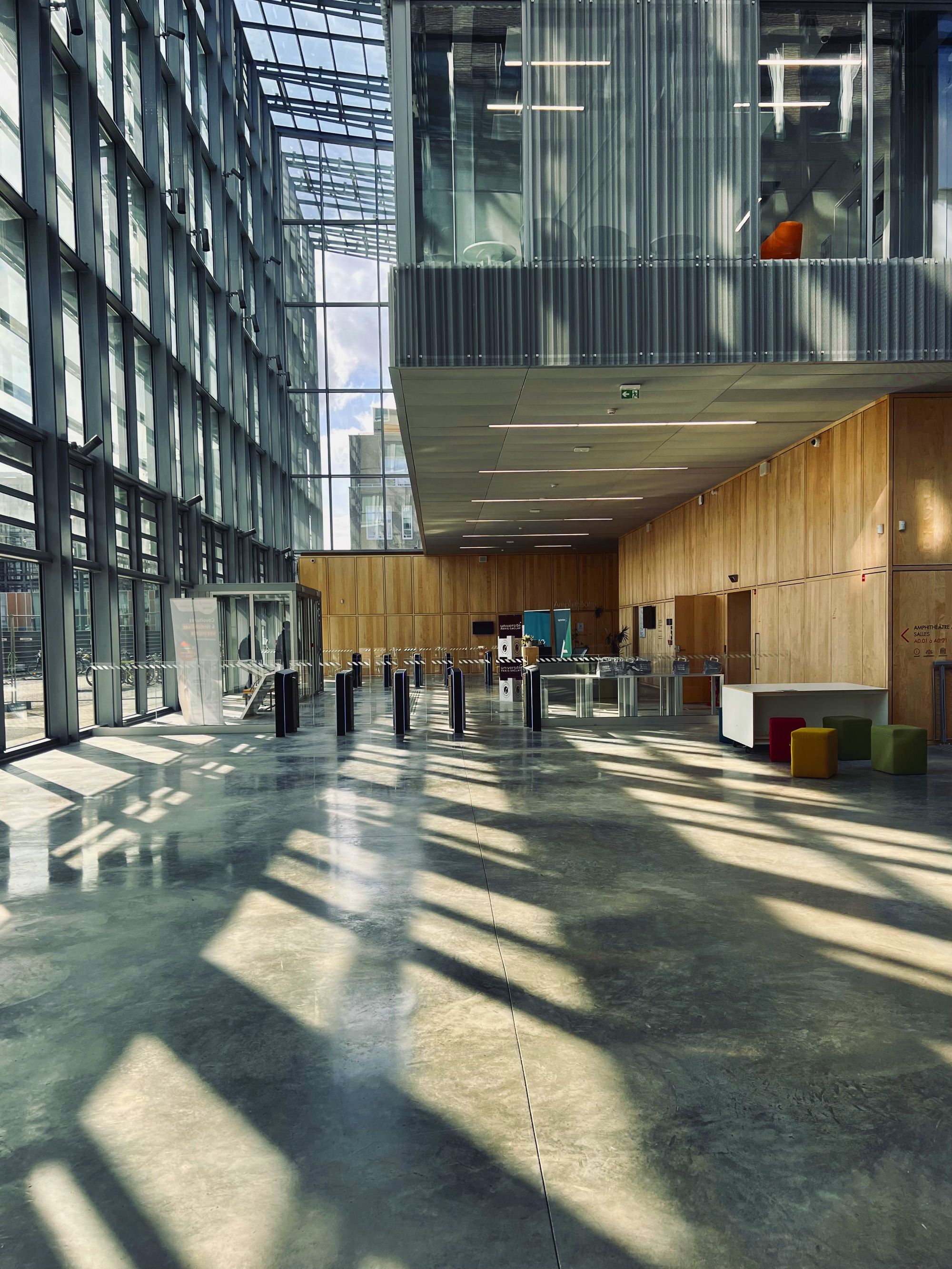 Lobby entrance with timber-clad reception desk and turnstiles beneath translucent ceiling panels filtering daylight