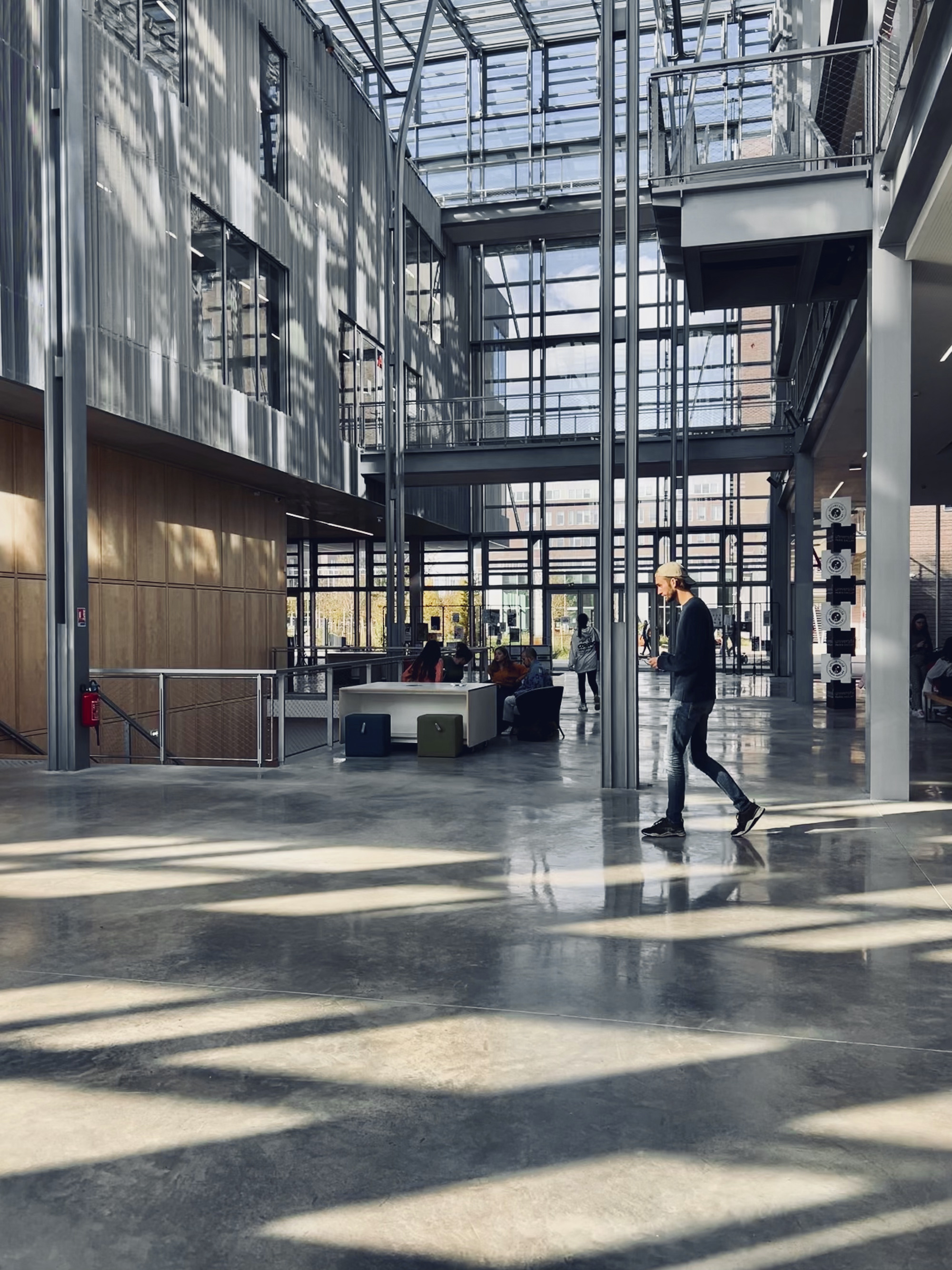 Atrium floor with patterned sunlight across polished concrete as a person walks past reception desk