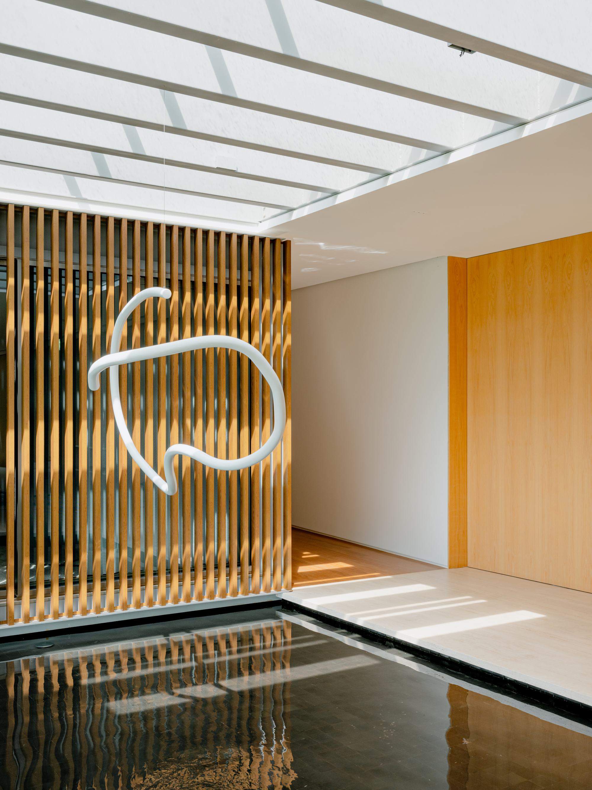 Interior water feature with vertical timber slat screen and white sculptural wall light