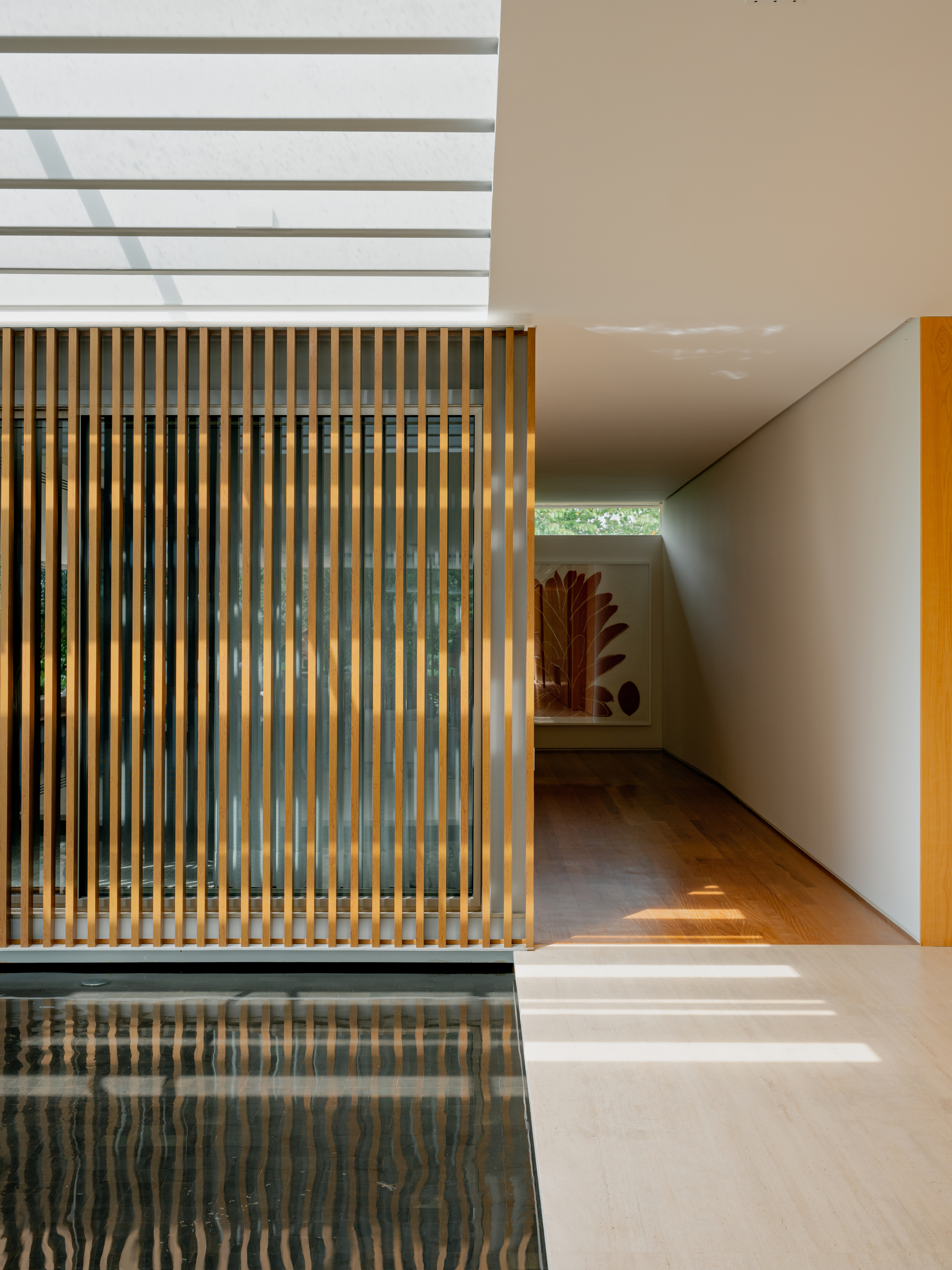 Corridor view past timber screen and reflecting pool toward angled ceiling with clerestory window