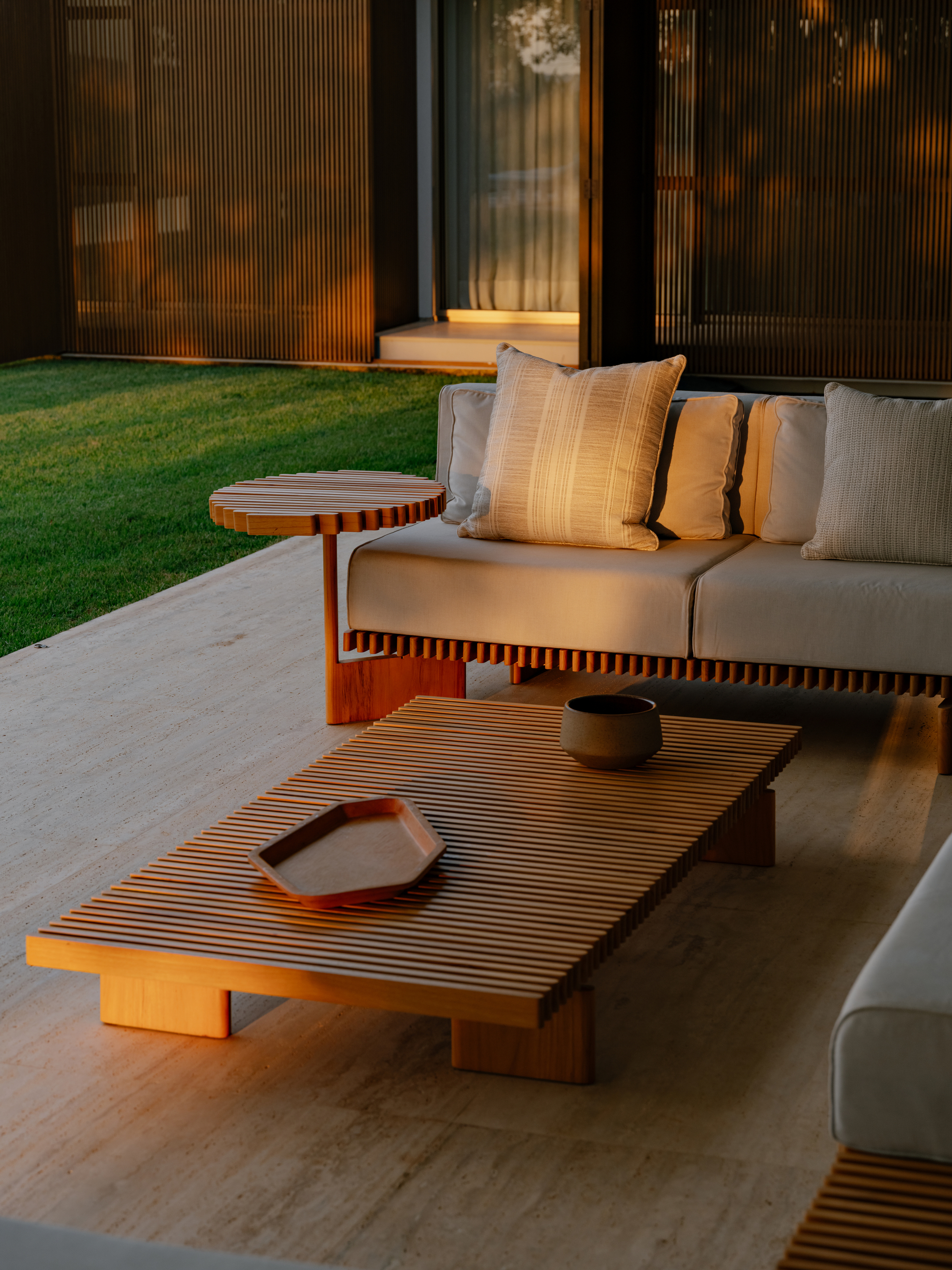 Slatted wood coffee table on the terrace at golden hour with corrugated screen panels behind