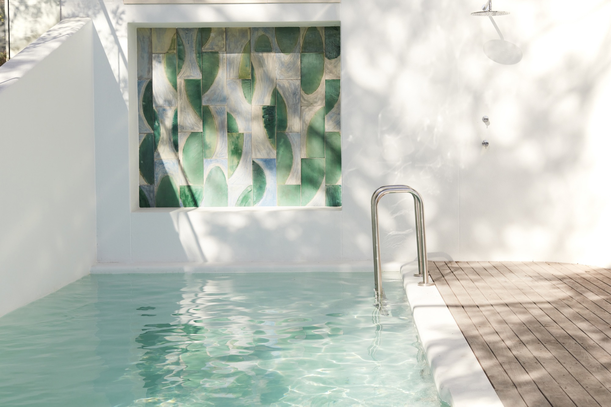 Courtyard pool with tiled mural and timber decking in dappled sunlight