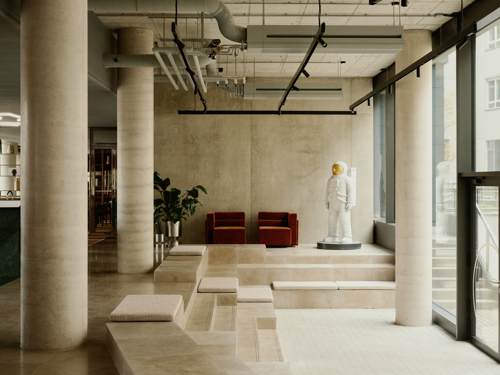 Raised platform with stone steps, cylindrical columns, and red velvet chairs near full-height windows