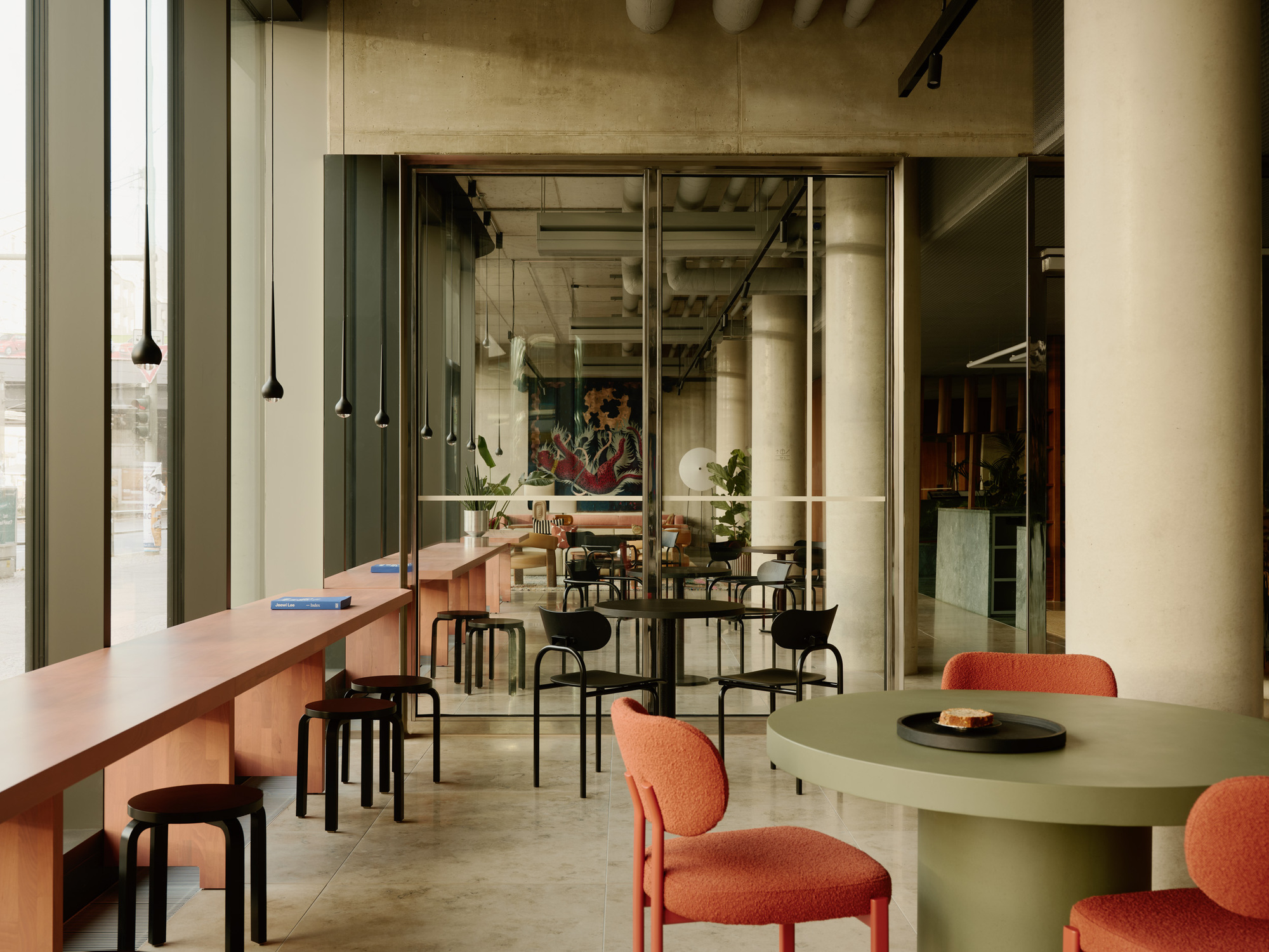 Dining area with pendant lights, mixed seating, and views through glass partitions to adjacent spaces