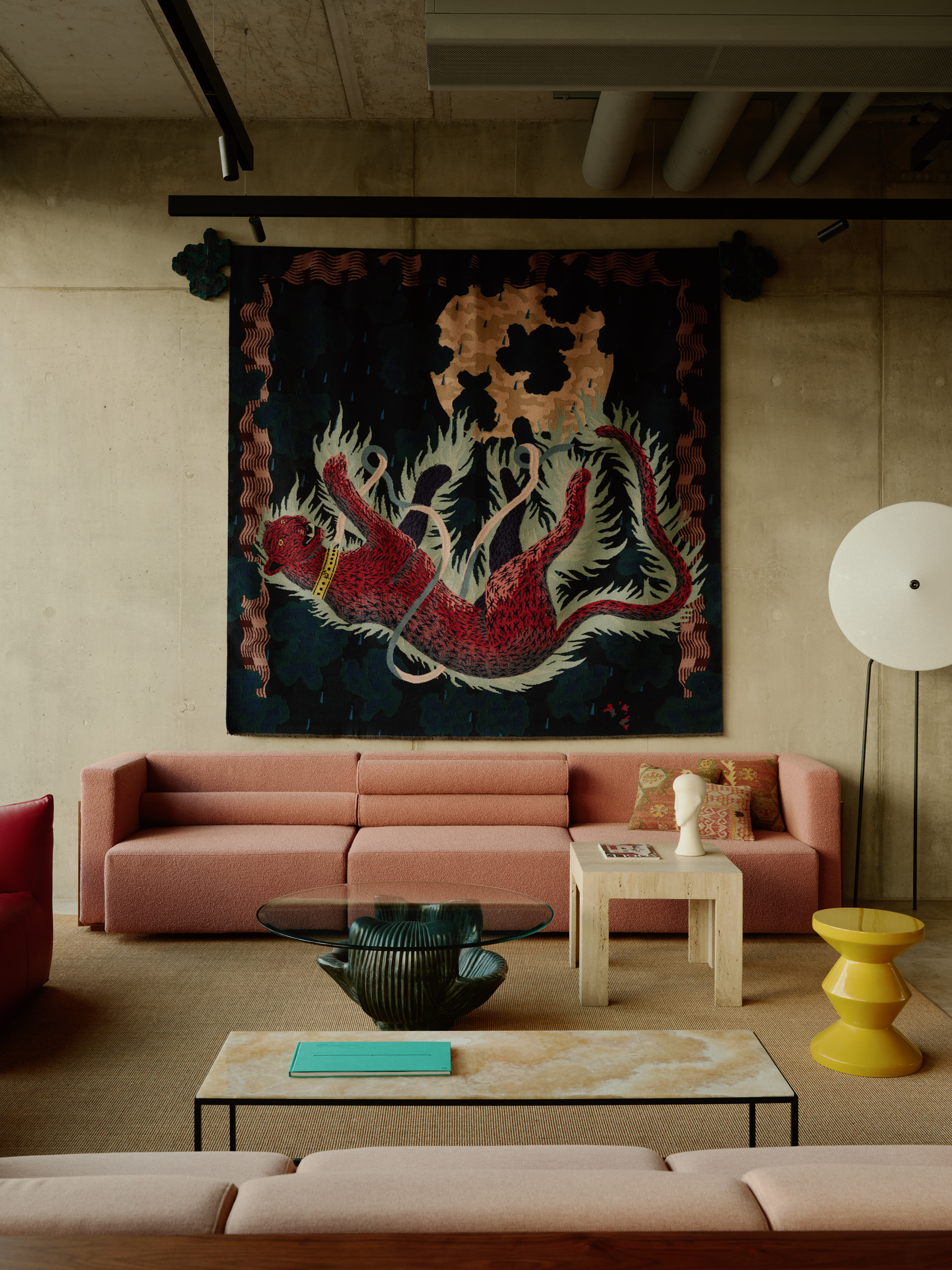 Close-up of seating beneath the dragon tapestry with exposed concrete ceiling and track lighting