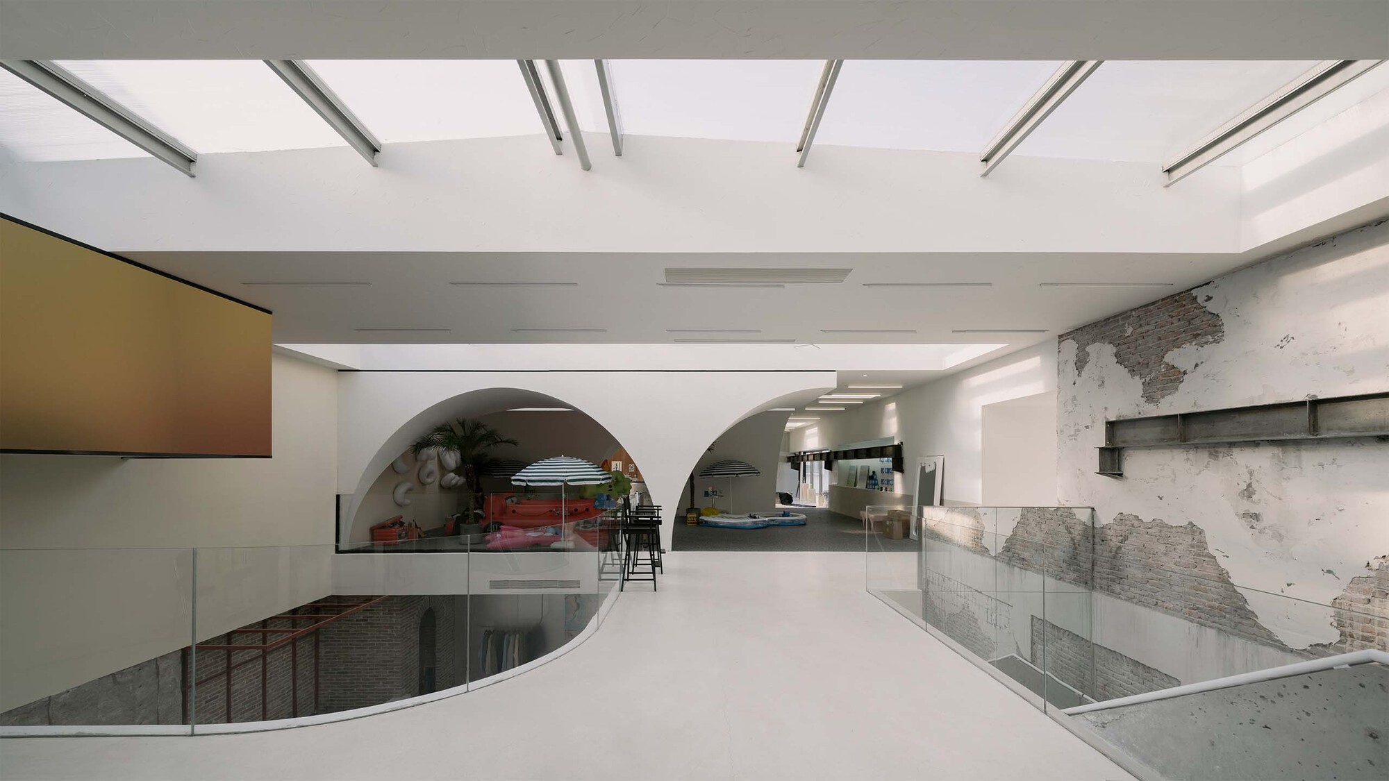 White epoxy floor with curved railing around stair void and arched openings beyond distressed plaster walls