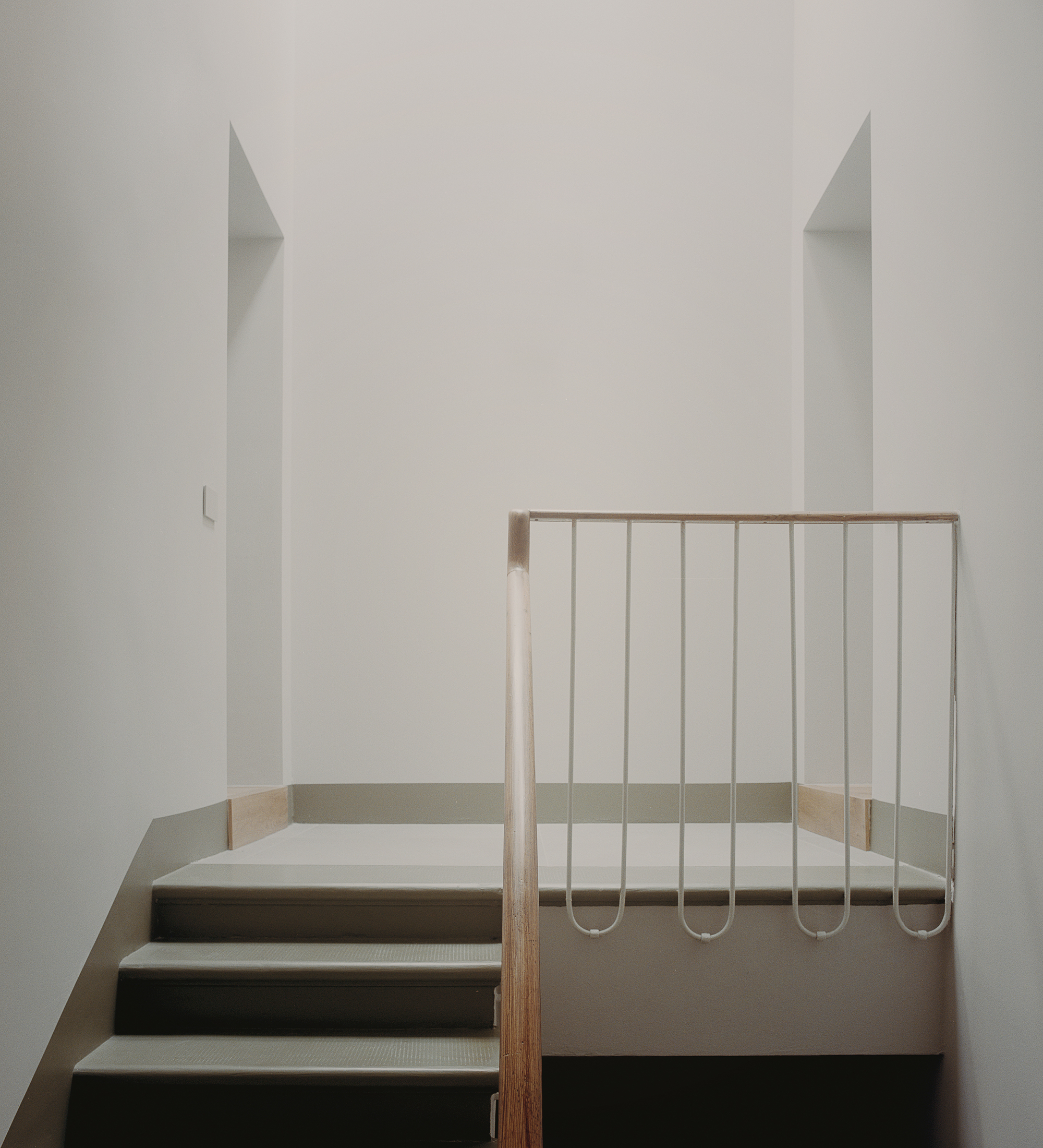 Steel rod balustrade with timber handrail at the stair landing in a white interior