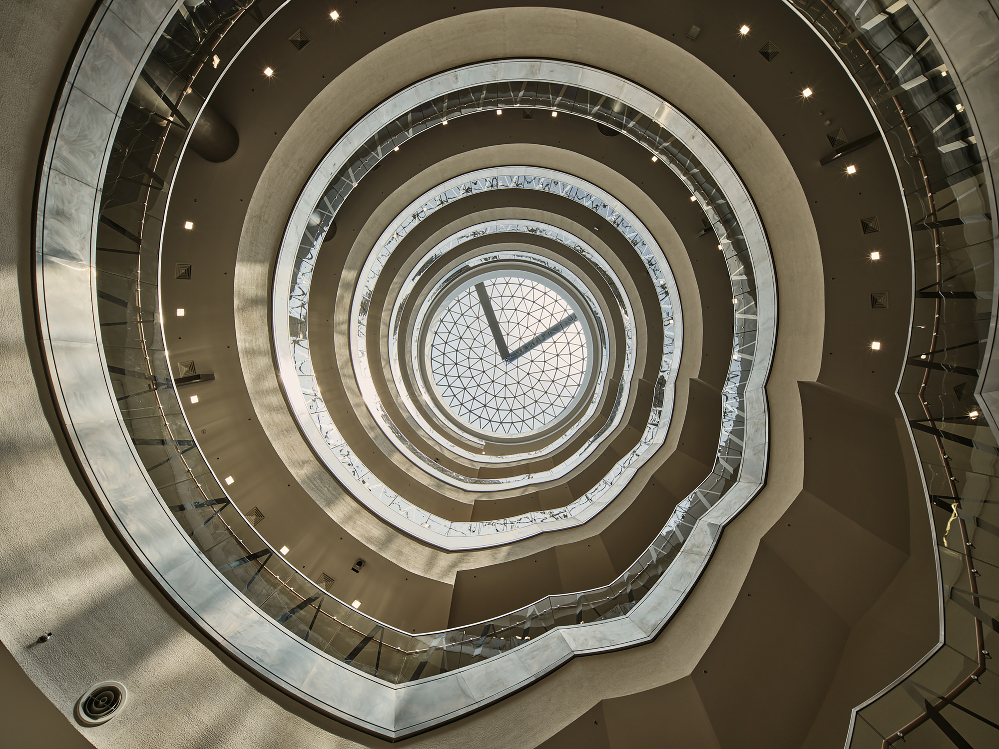Looking up through the circular atrium well showing concentric rings of balconies to a geometric skylight