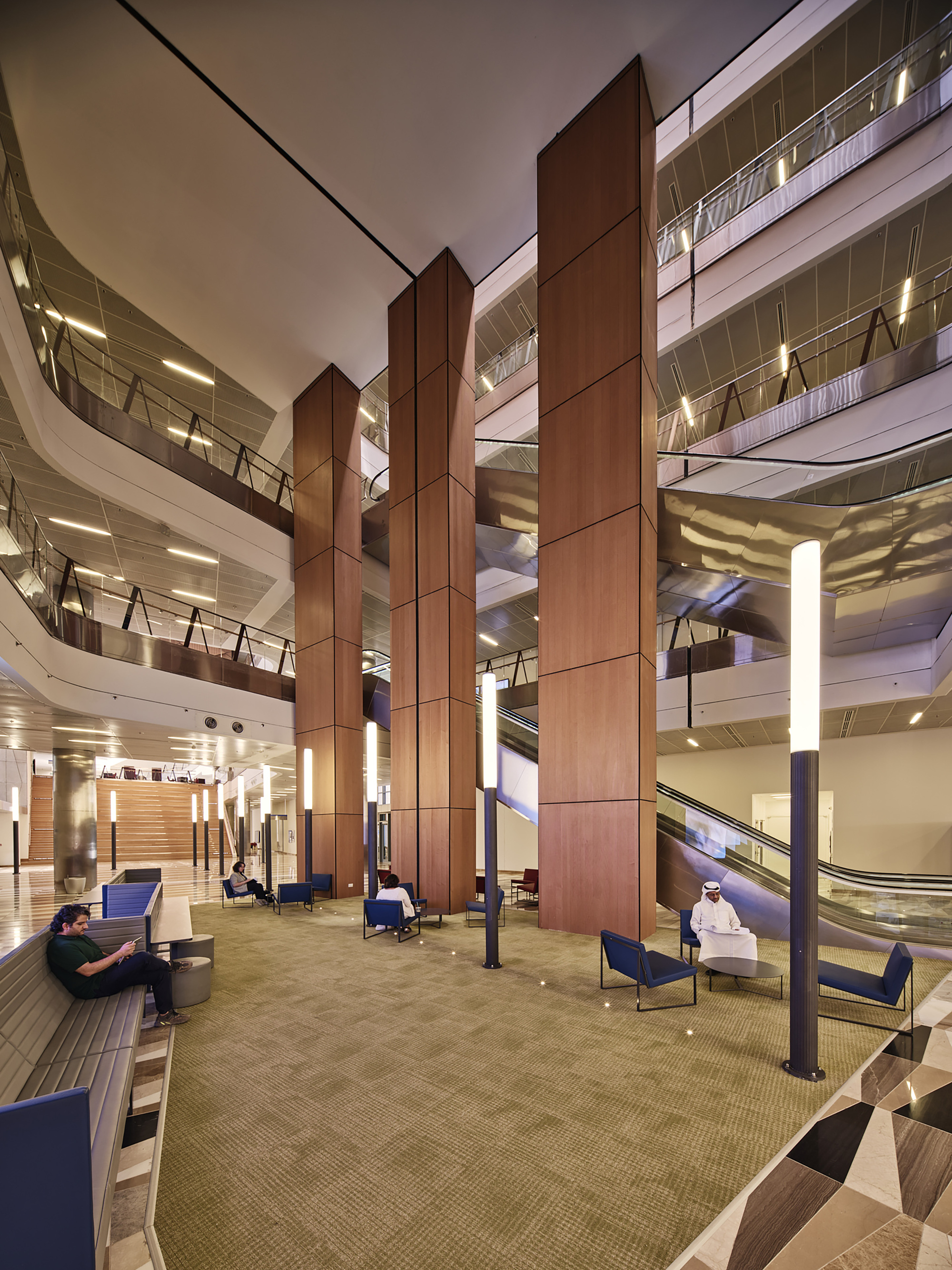 Atrium lobby with tall timber-paneled columns and carpeted seating area at dusk