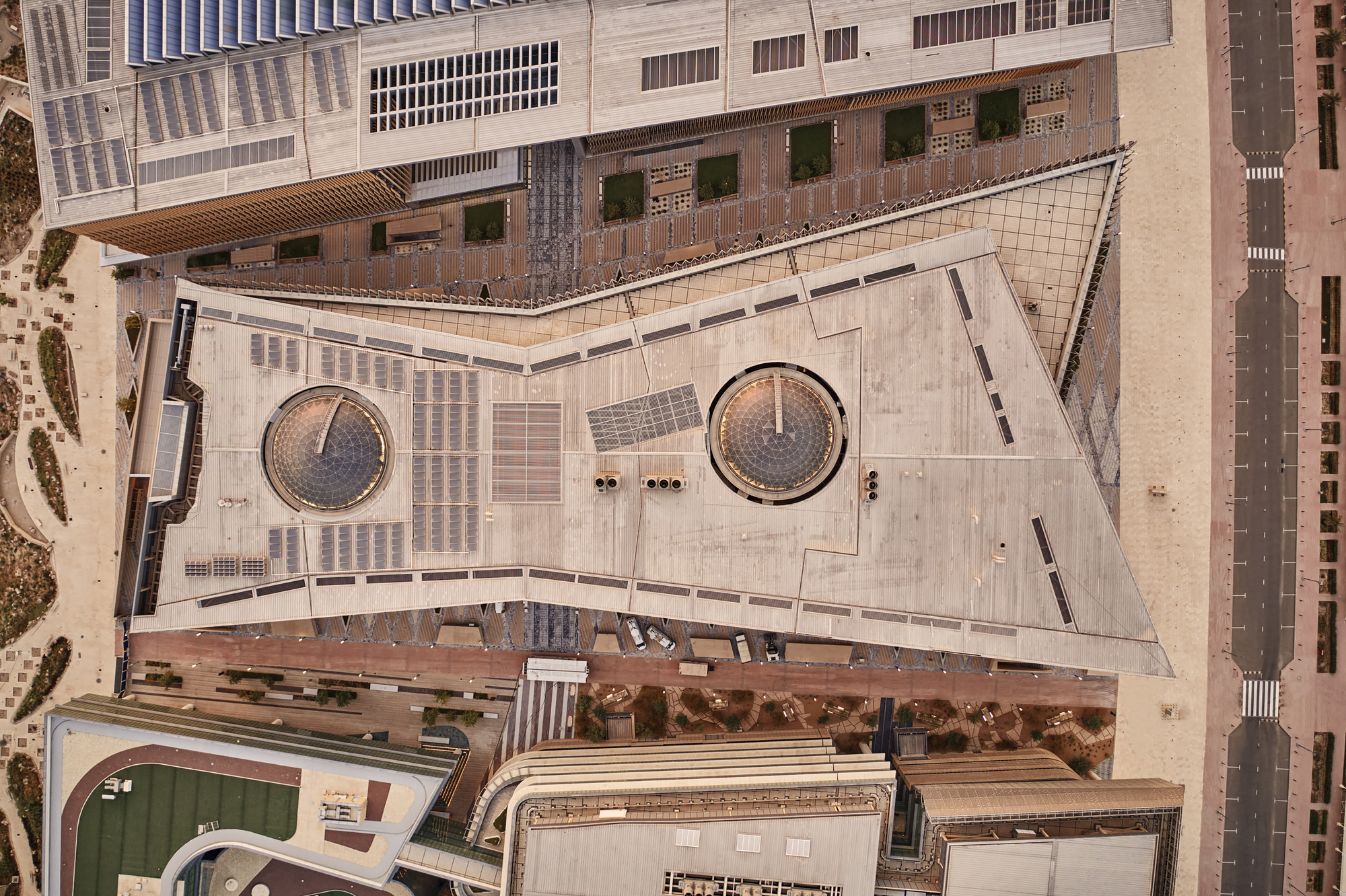 Aerial view of triangular concrete plaza with two circular planters and pedestrians below