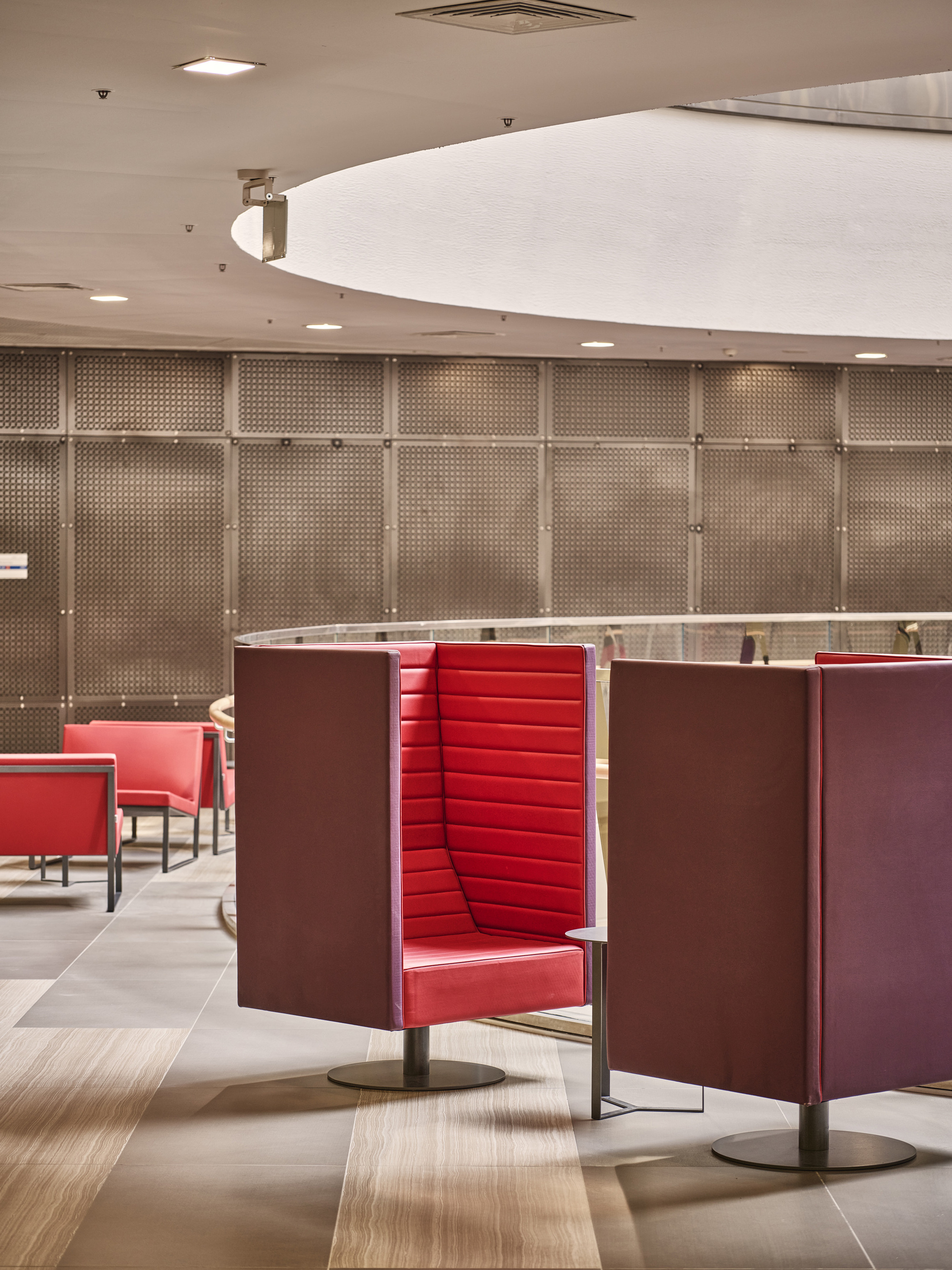 Red upholstered booth seating with privacy screens beneath a curved white ceiling soffit
