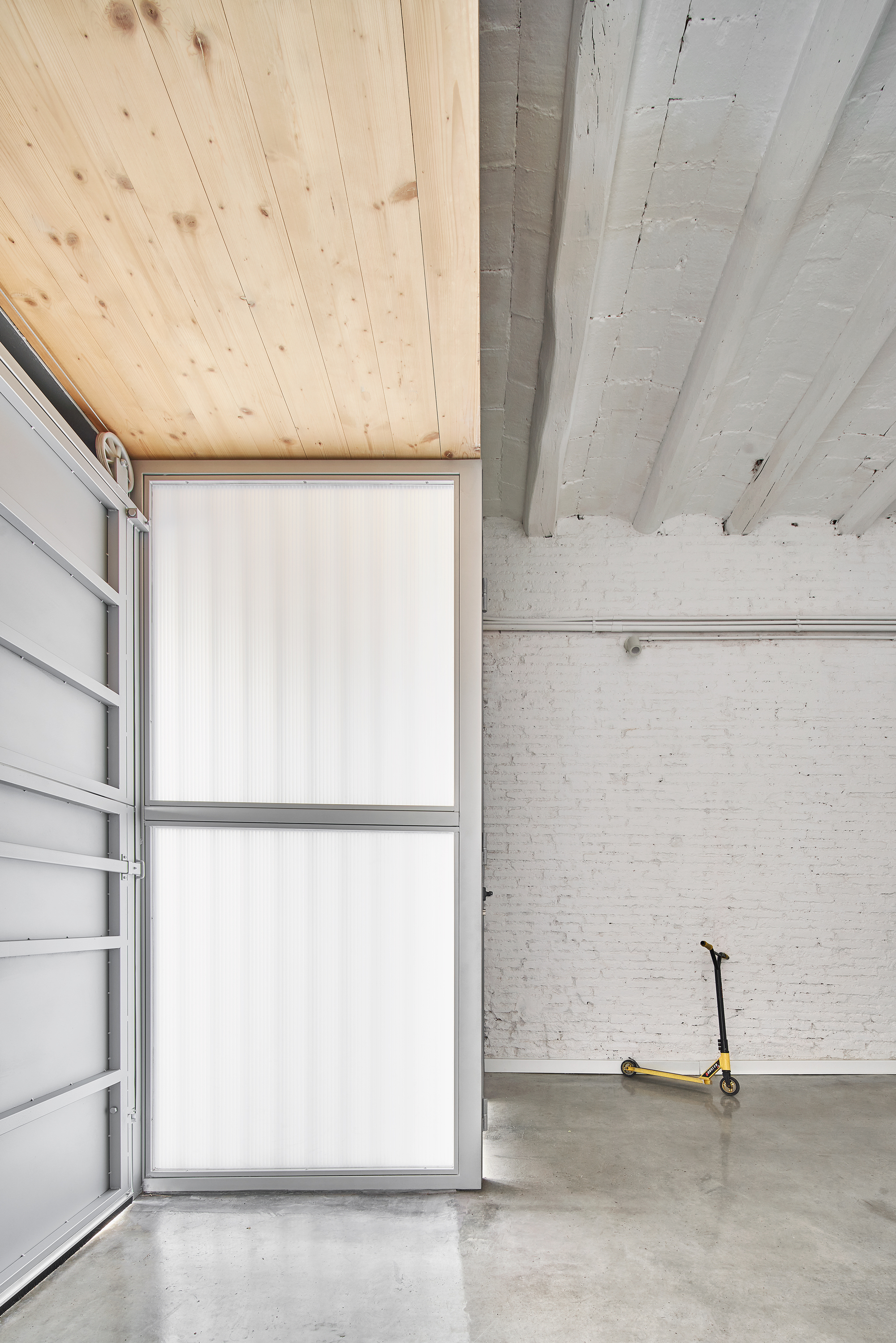 Scooter on polished concrete floor beneath transition from plywood to whitewashed timber ceiling planks