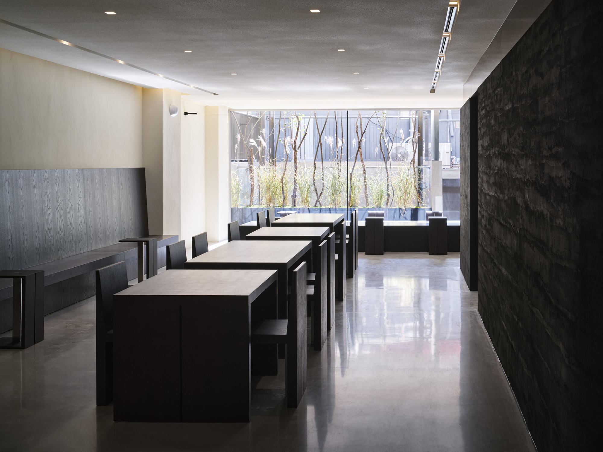 Dining room with dark tables facing a courtyard window lined with bare trees