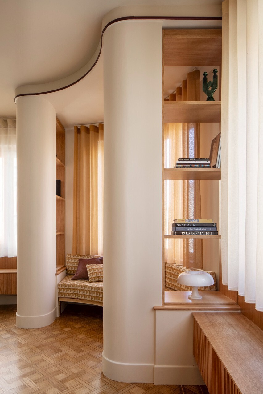 Curved white column next to timber shelving and staircase with parquet flooring