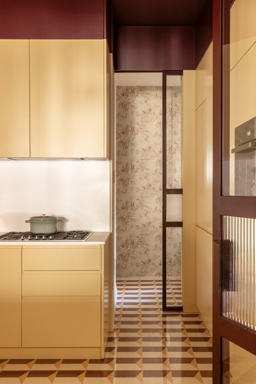 Corridor view showing floral wallpaper panel and chequered floor connecting kitchen to hallway